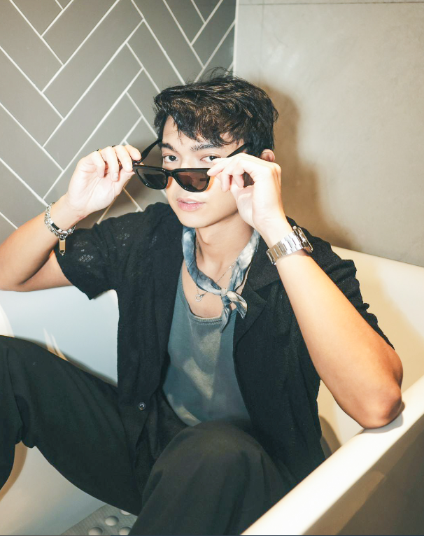 A guest wearing sunglasses is sitting in a bathtub