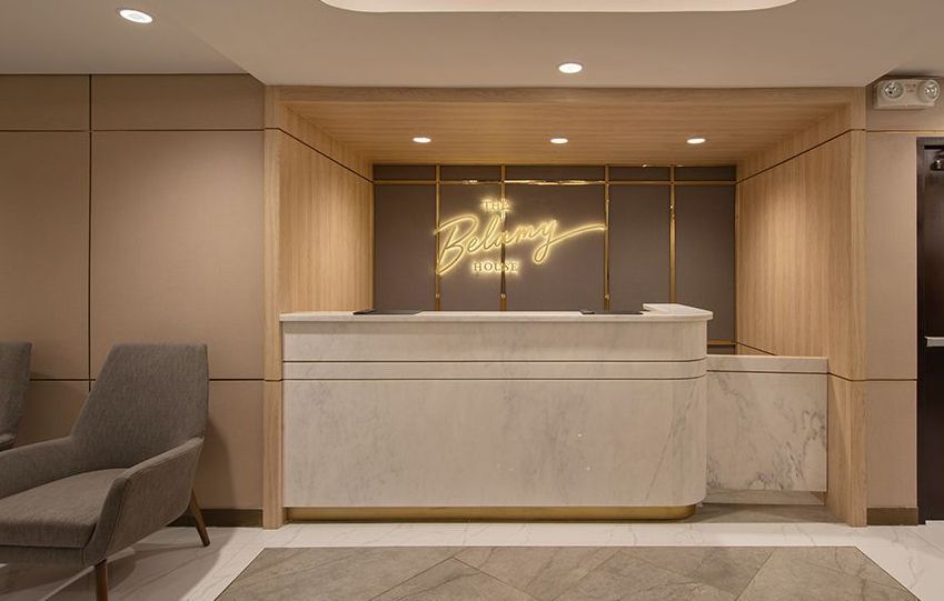 Modern hotel reception desk in a beige lobby with warm lighting and seating area