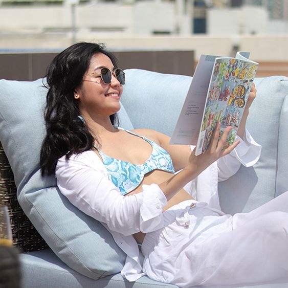 Sunbathing while reading a book at the rooftop swimming pool.
