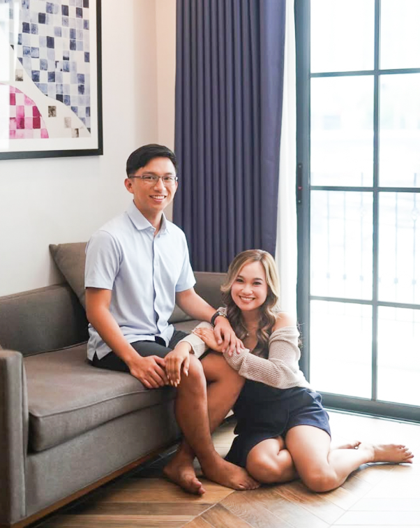 Couple relaxing in their spacious hotel room with large windows and modern furnishings.
