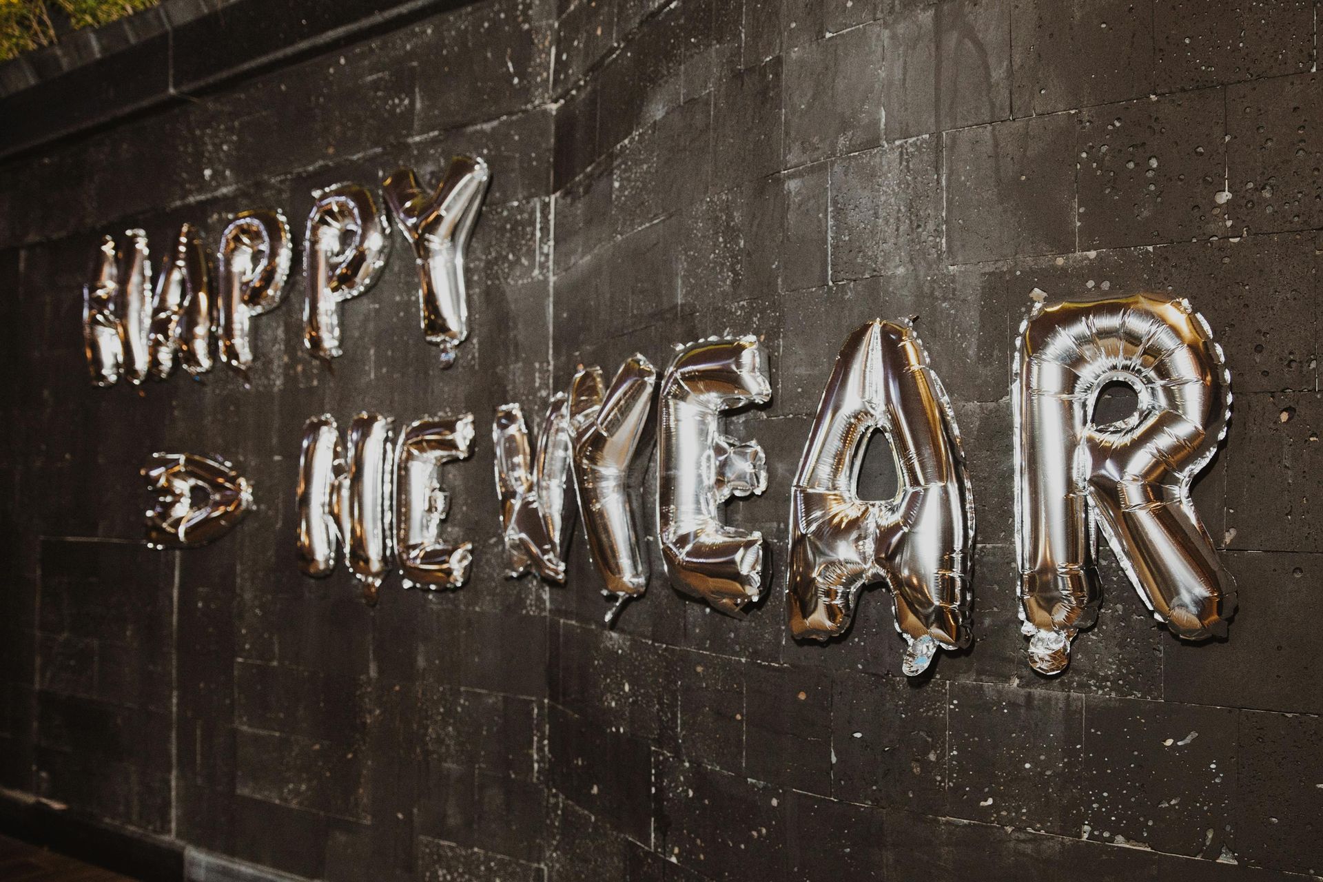 silver colored happy new year balloons on wall