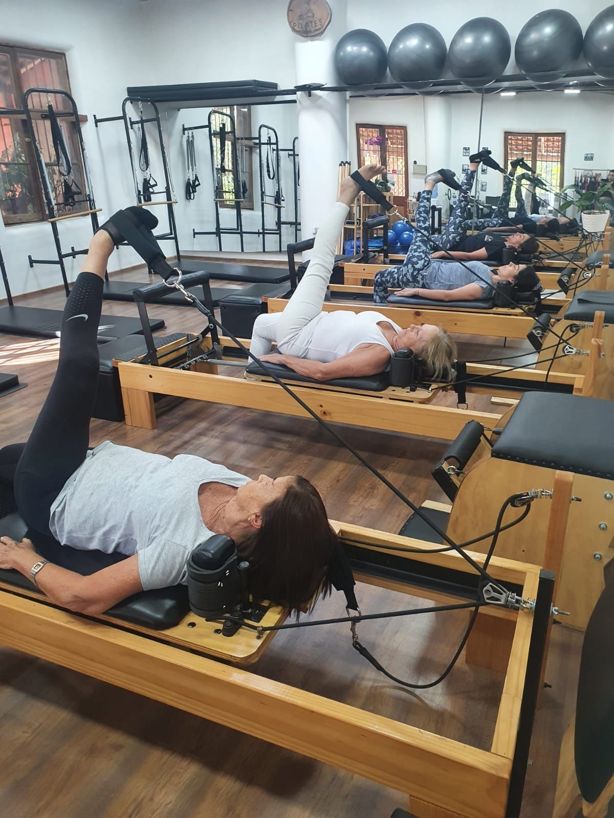 Un grupo de mujeres están acostadas en máquinas de pilates en un gimnasio.