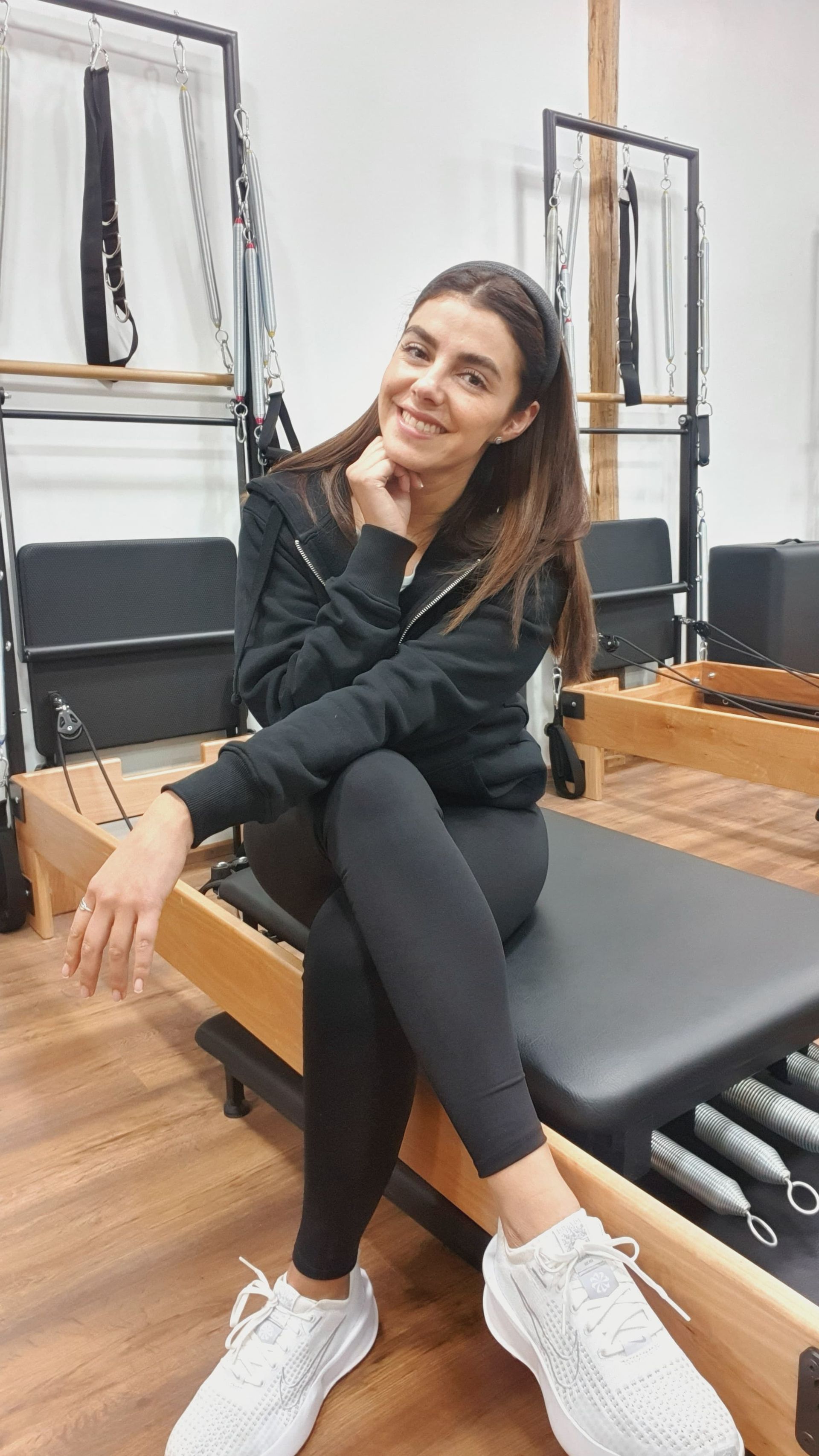 Una mujer está sentada en una máquina de pilates en un gimnasio.