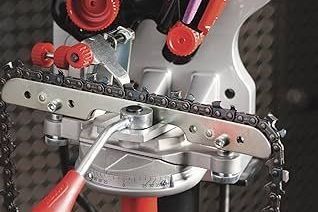 A chainsaw chain sharpening tool with a chain in place, red and silver.