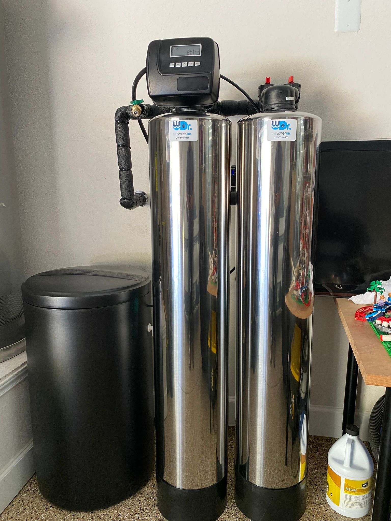 Water softener system with two silver tanks, a black control unit, and a salt storage bin.