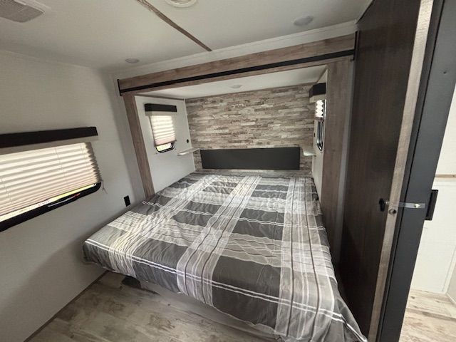 RV bedroom with a bed, window, and gray and wood accent wall.