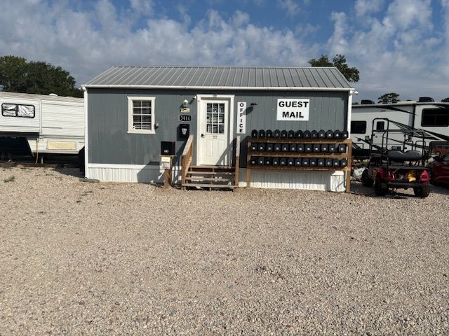 A small grey building with guest mailboxes. An RV and golf cart are also present.