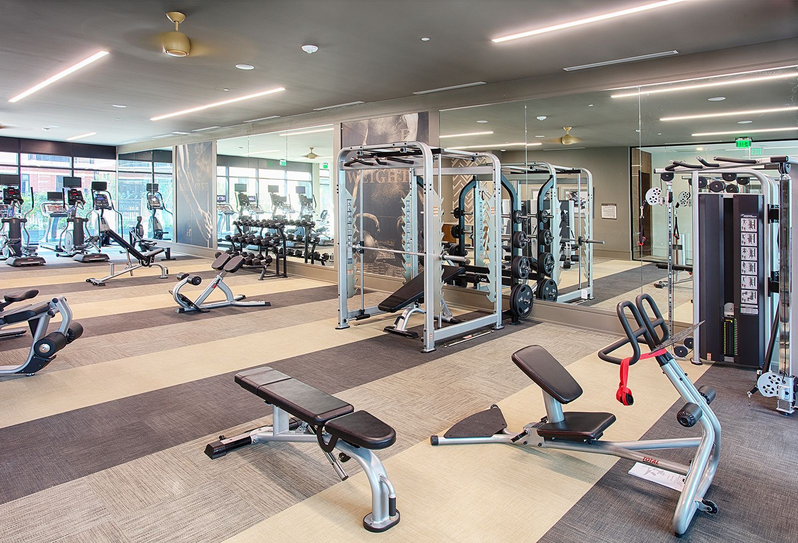 Gym interior with various exercise machines and weights.