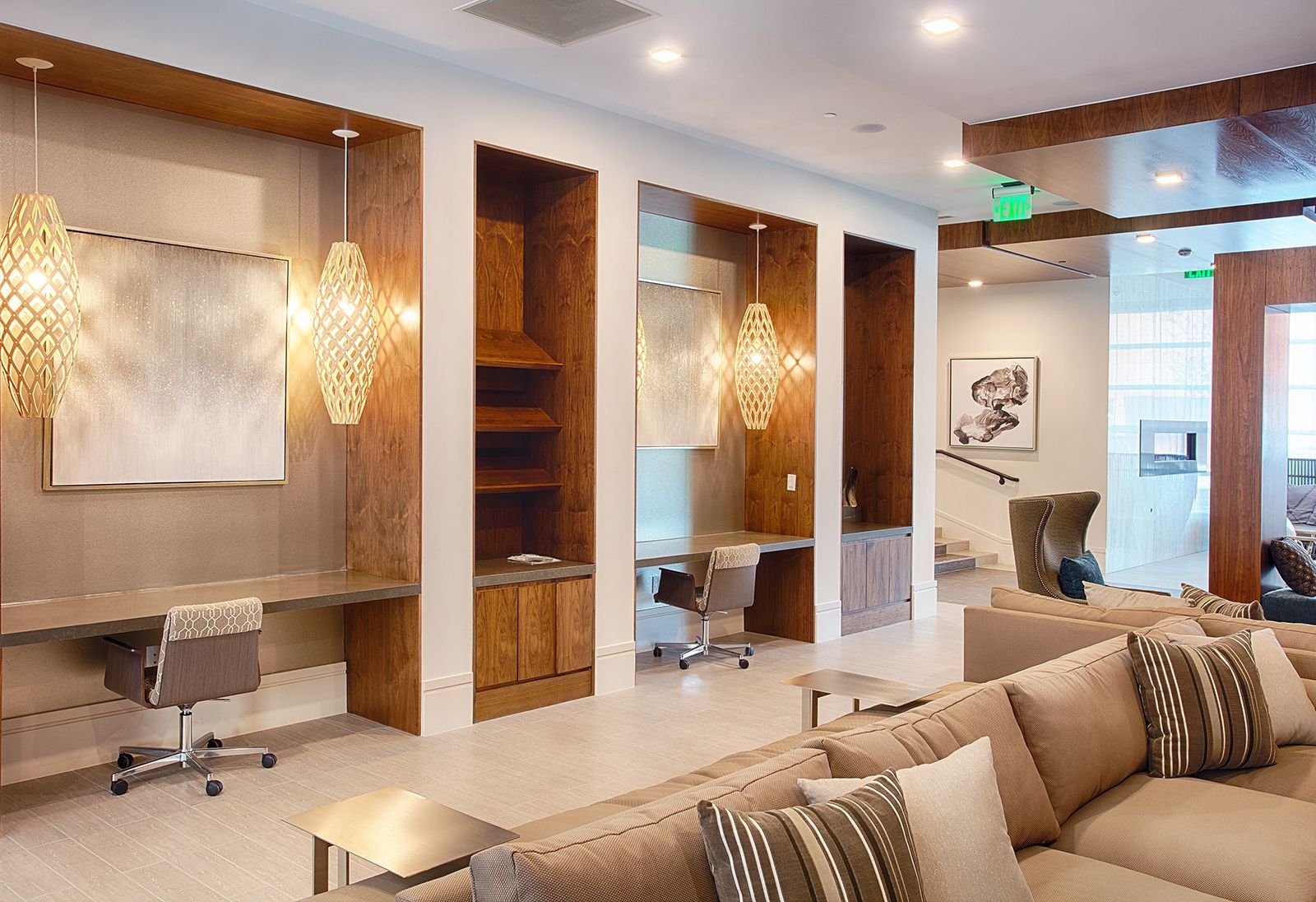 Cozy lounge with desks in alcoves and sofa. Warm tones with decorative lighting.