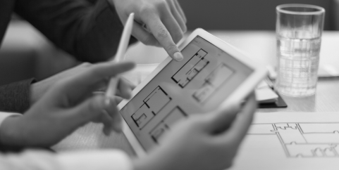 Black and white images of two people pointing at the IPad with apartment floor plan layouts.