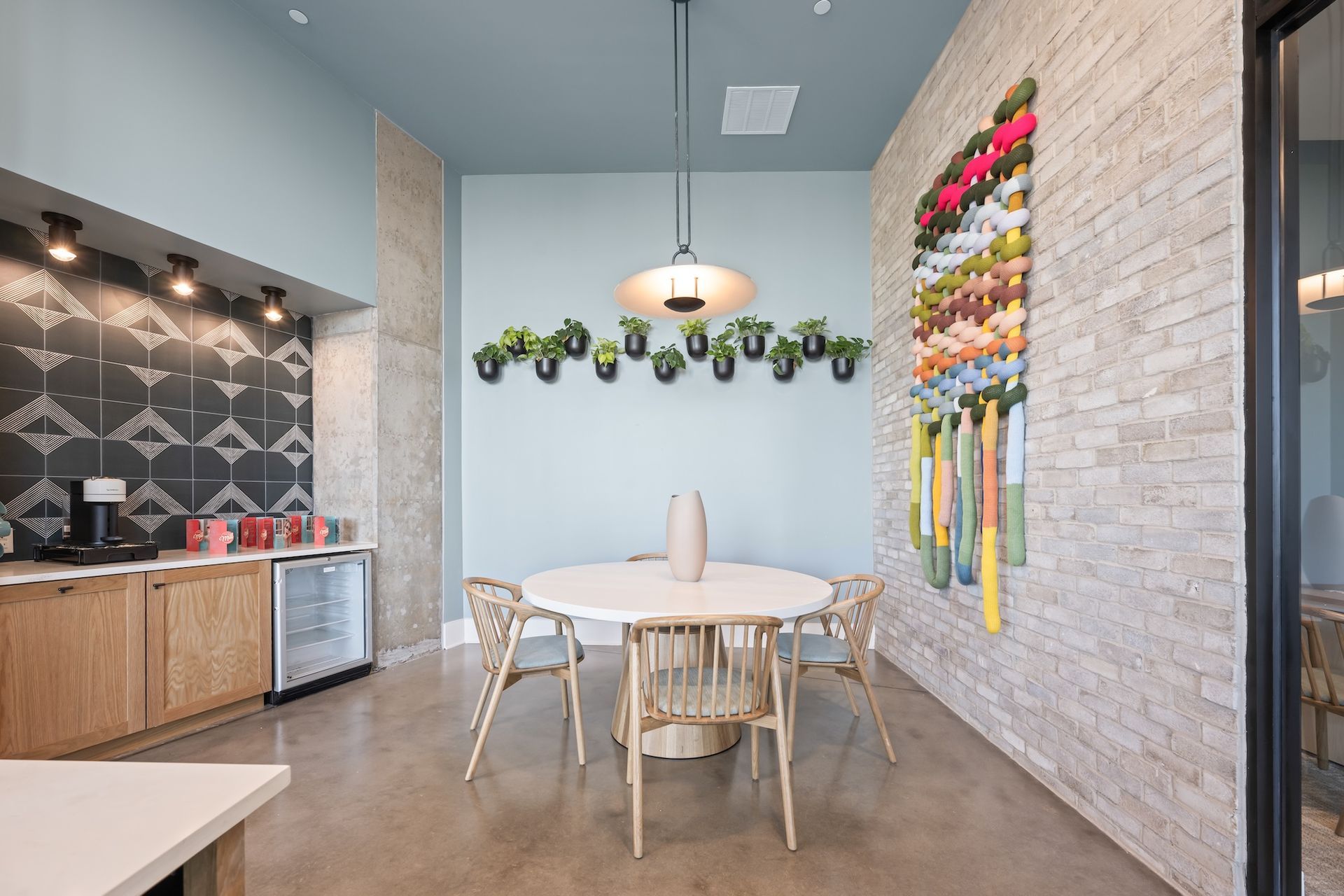 Modern dining nook with round table, chairs, decorative wall art, and coffee station.