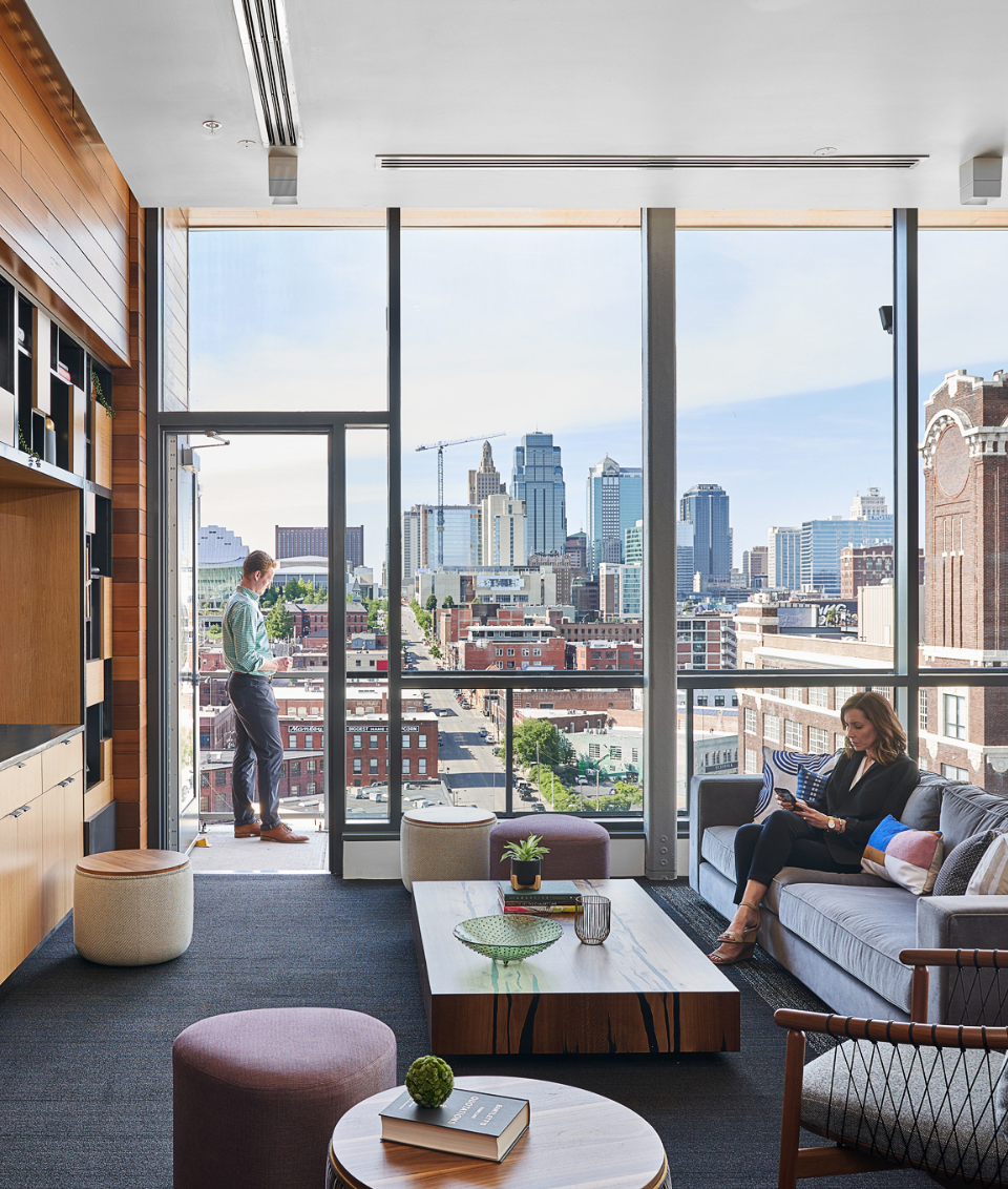 A woman is sitting on a couch in a living room with a view of the city.