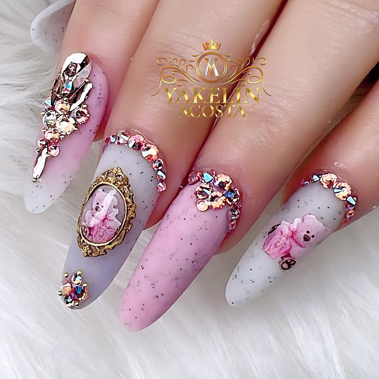 A woman 's nails are decorated with rhinestones and a teddy bear.
