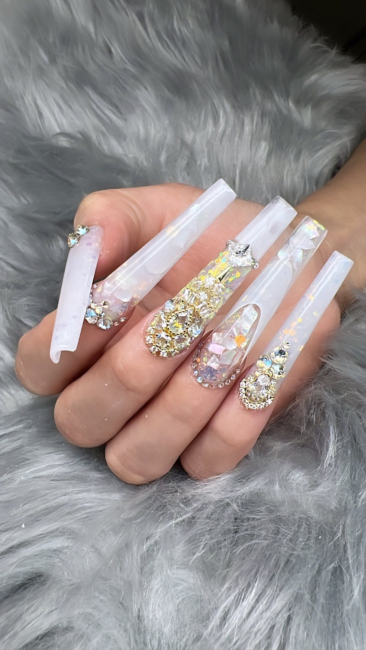 A close up of a person 's hand with long nails and rhinestones.
