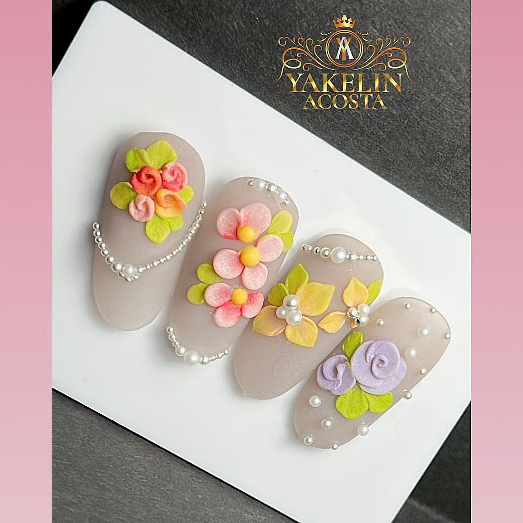 A white plate topped with four nails decorated with flowers and pearls.