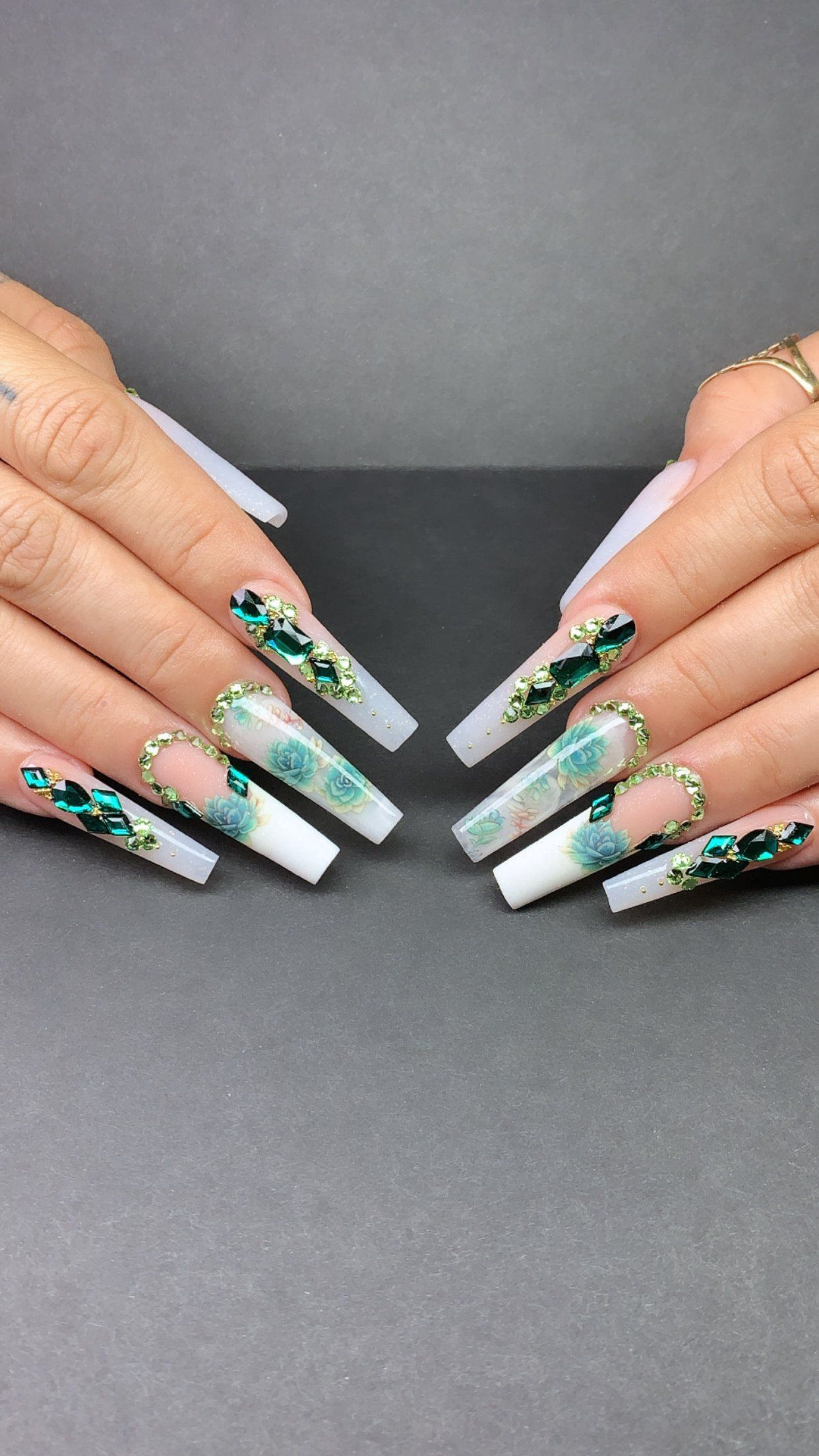 A close up of a woman 's nails with a green and white design.