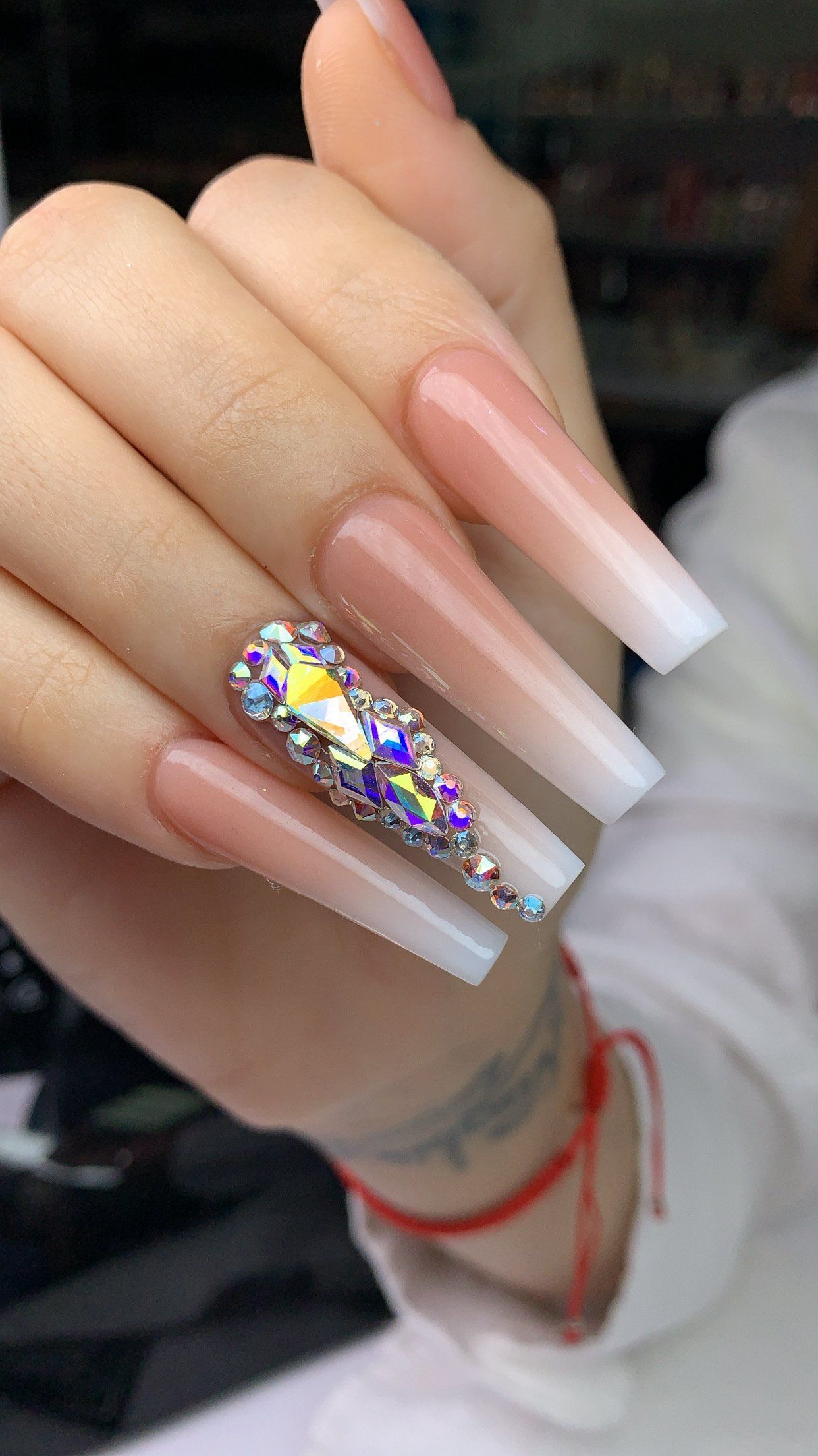A close up of a person 's hand with long nails and rhinestones.