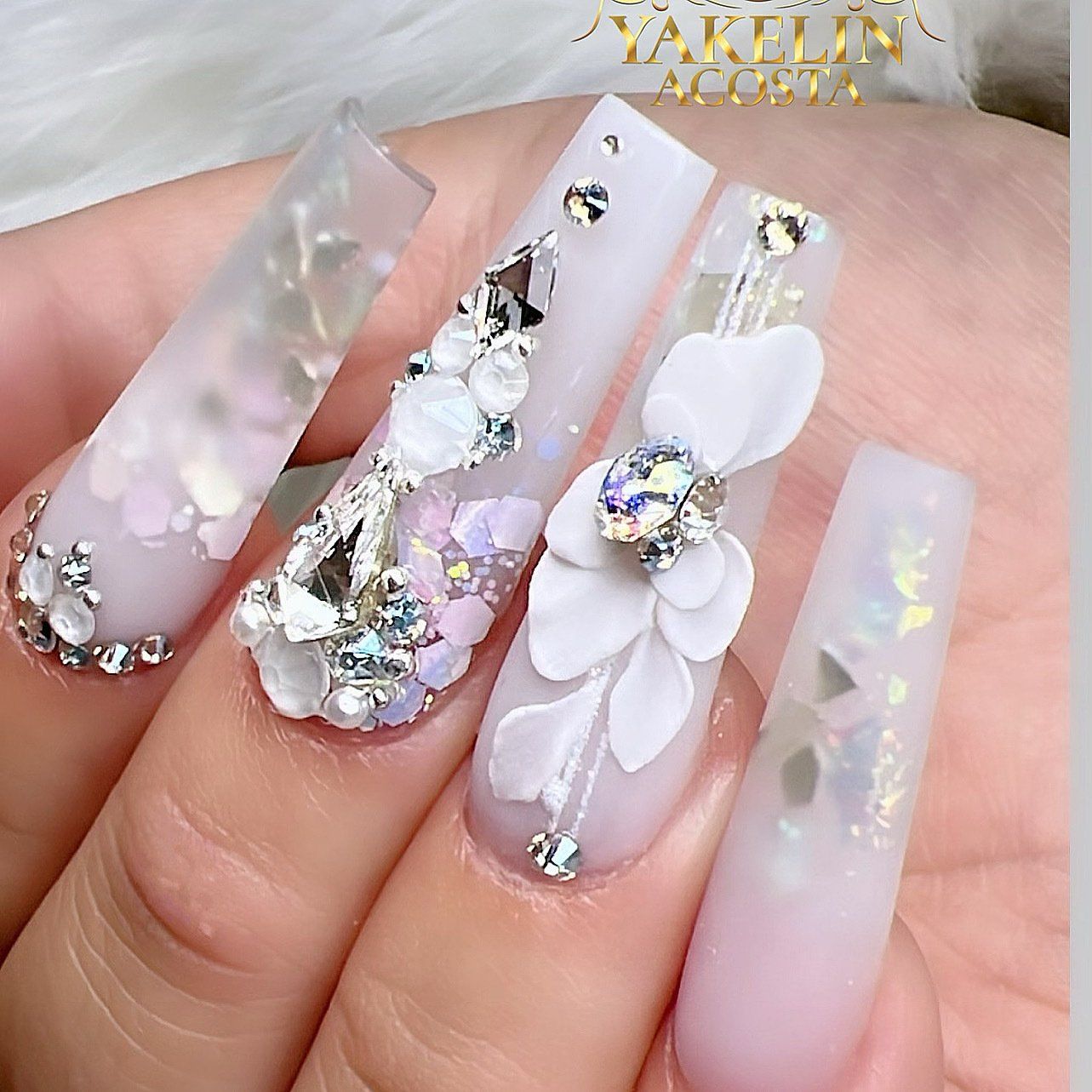 A close up of a woman 's nails with flowers and rhinestones.