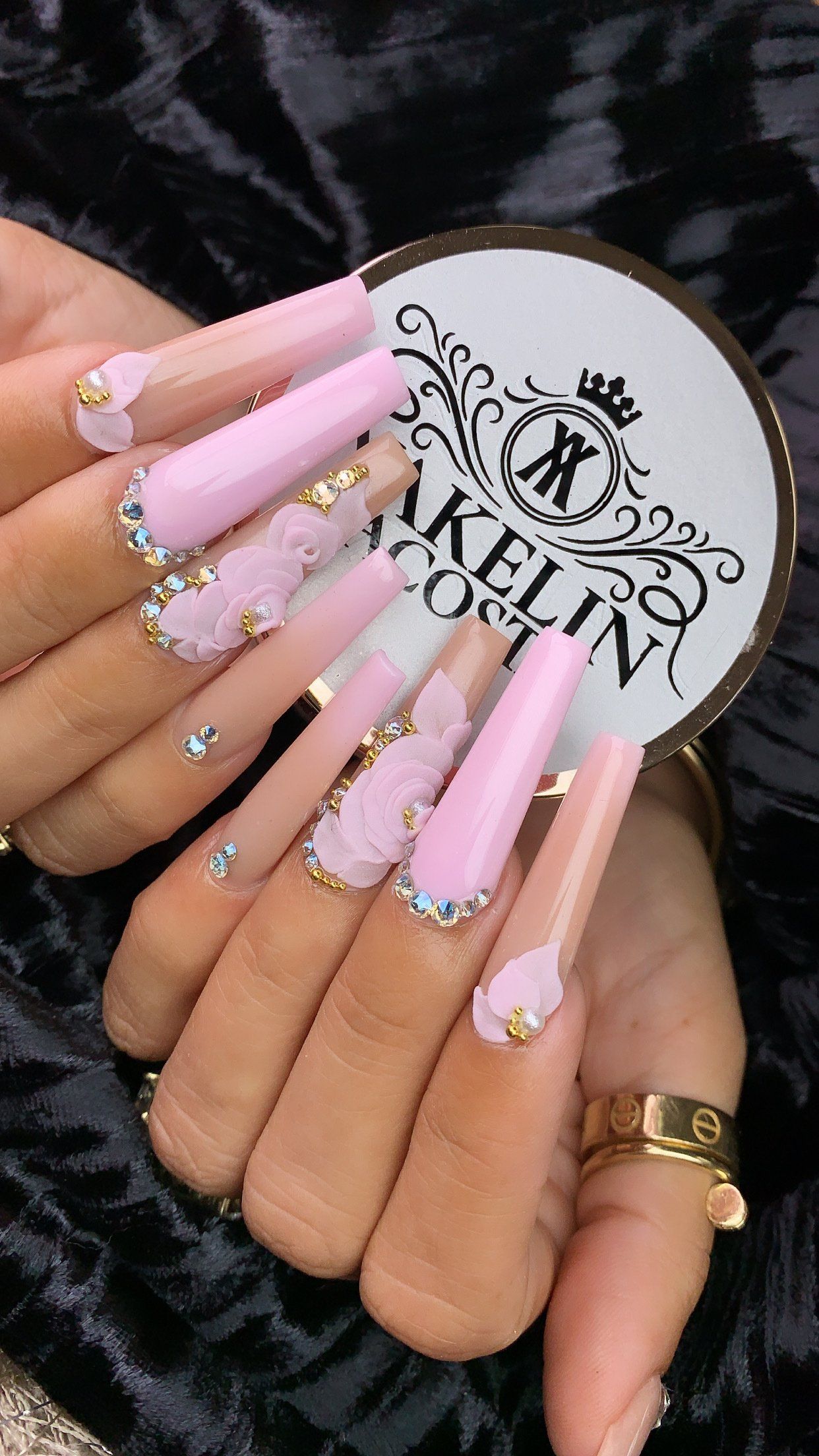 A close up of a woman 's hand with long pink nails and a ring.