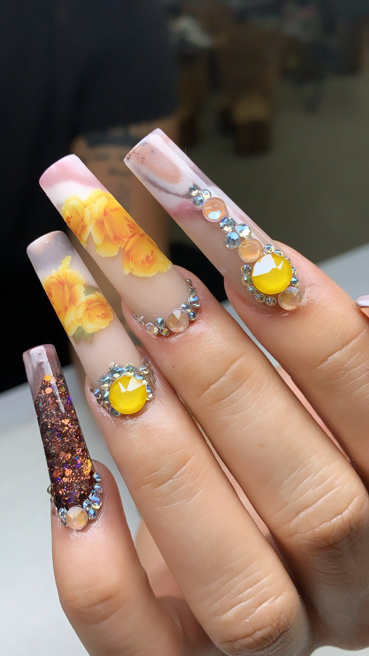 A close up of a woman 's nails with a candy corn design and rhinestones.