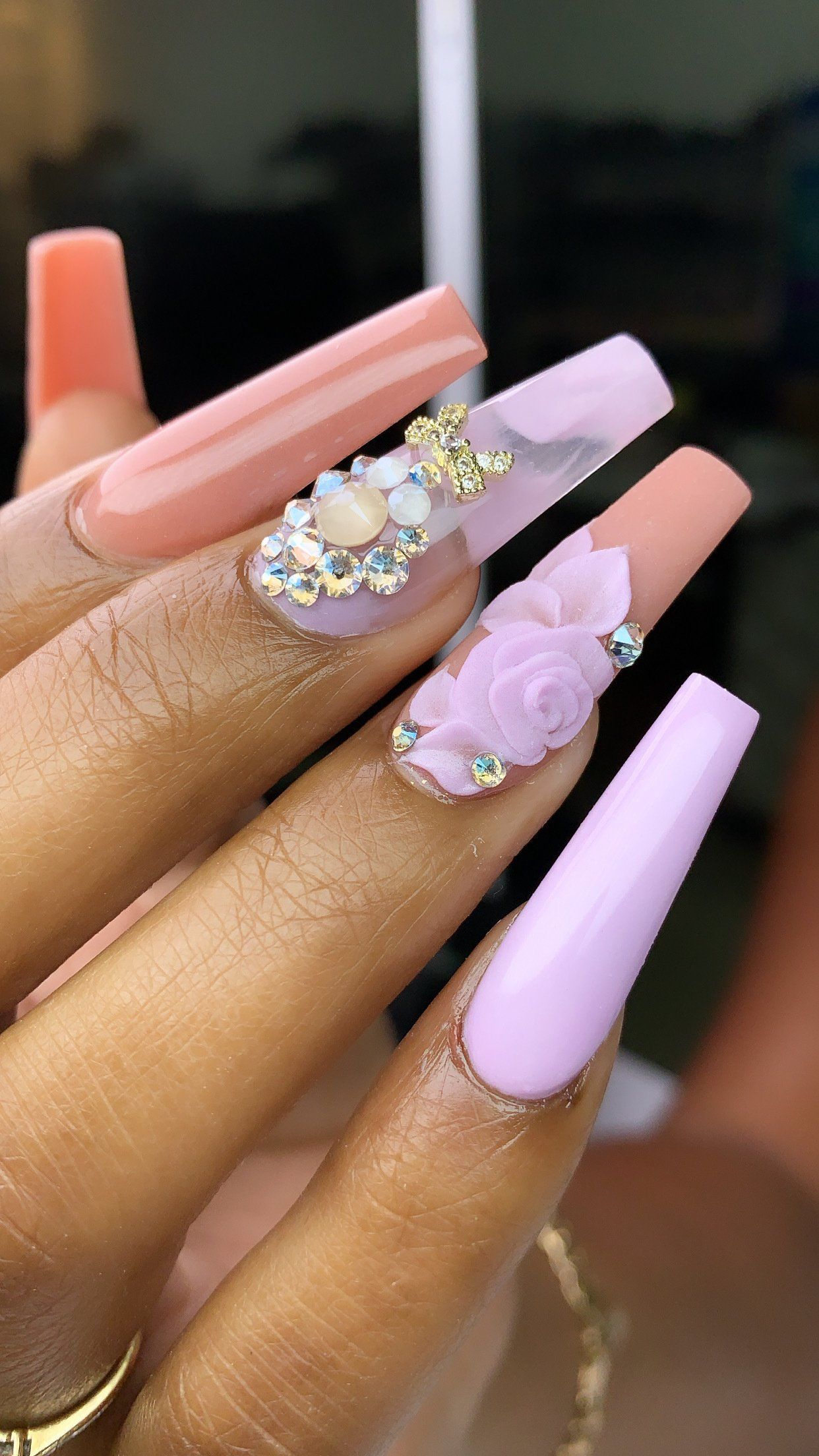 A close up of a woman 's nails with rhinestones and flowers.