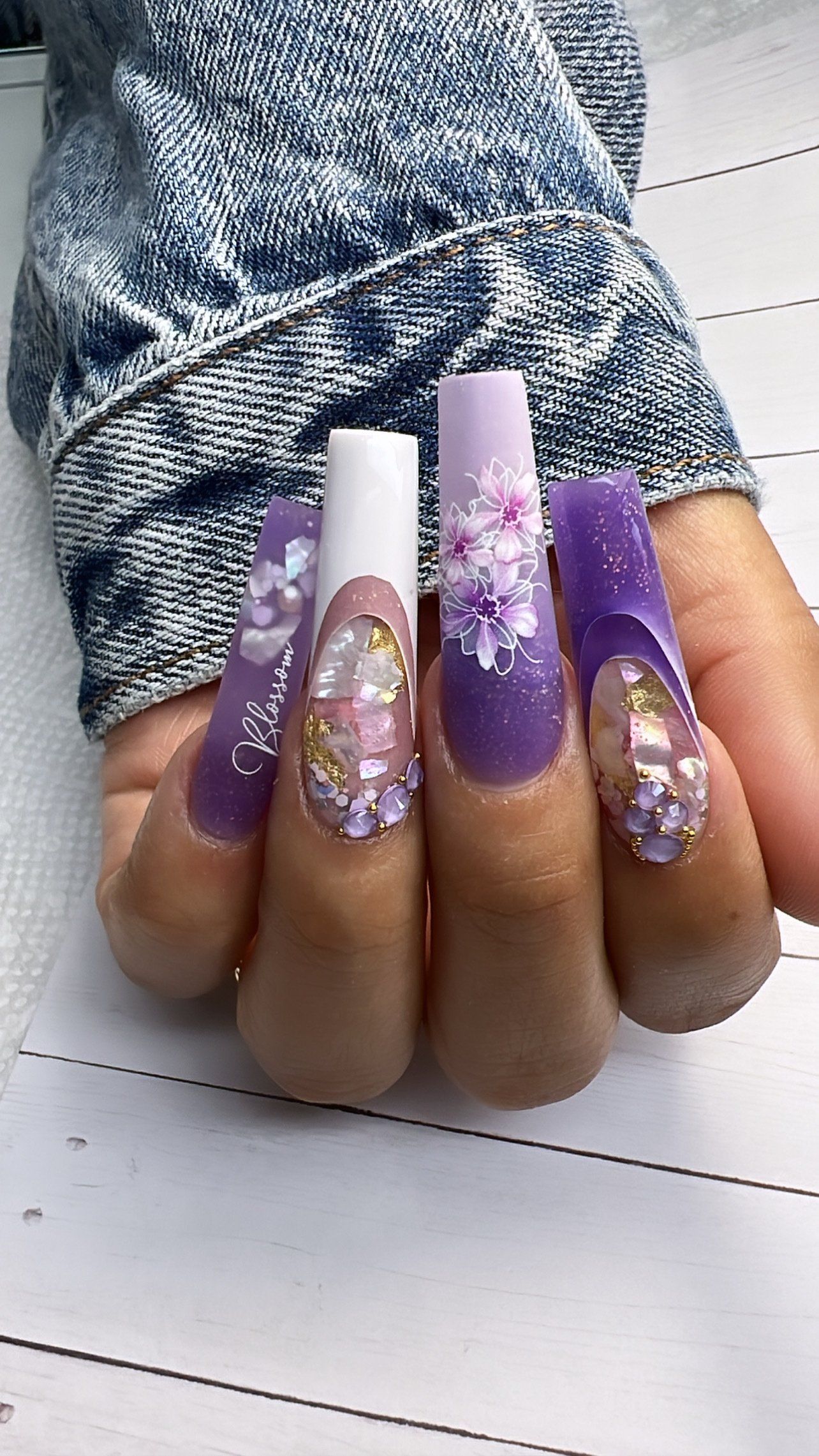 A close up of a person 's hand with long purple and white nails.