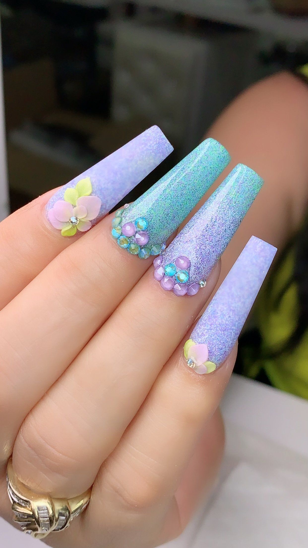 A close up of a person 's hand with long nails and a ring.