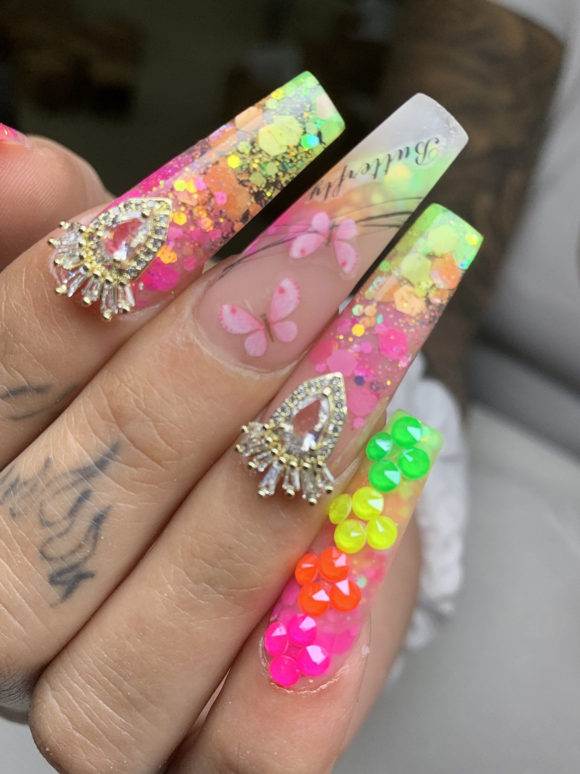 A close up of a person 's nails with neon colors and rhinestones