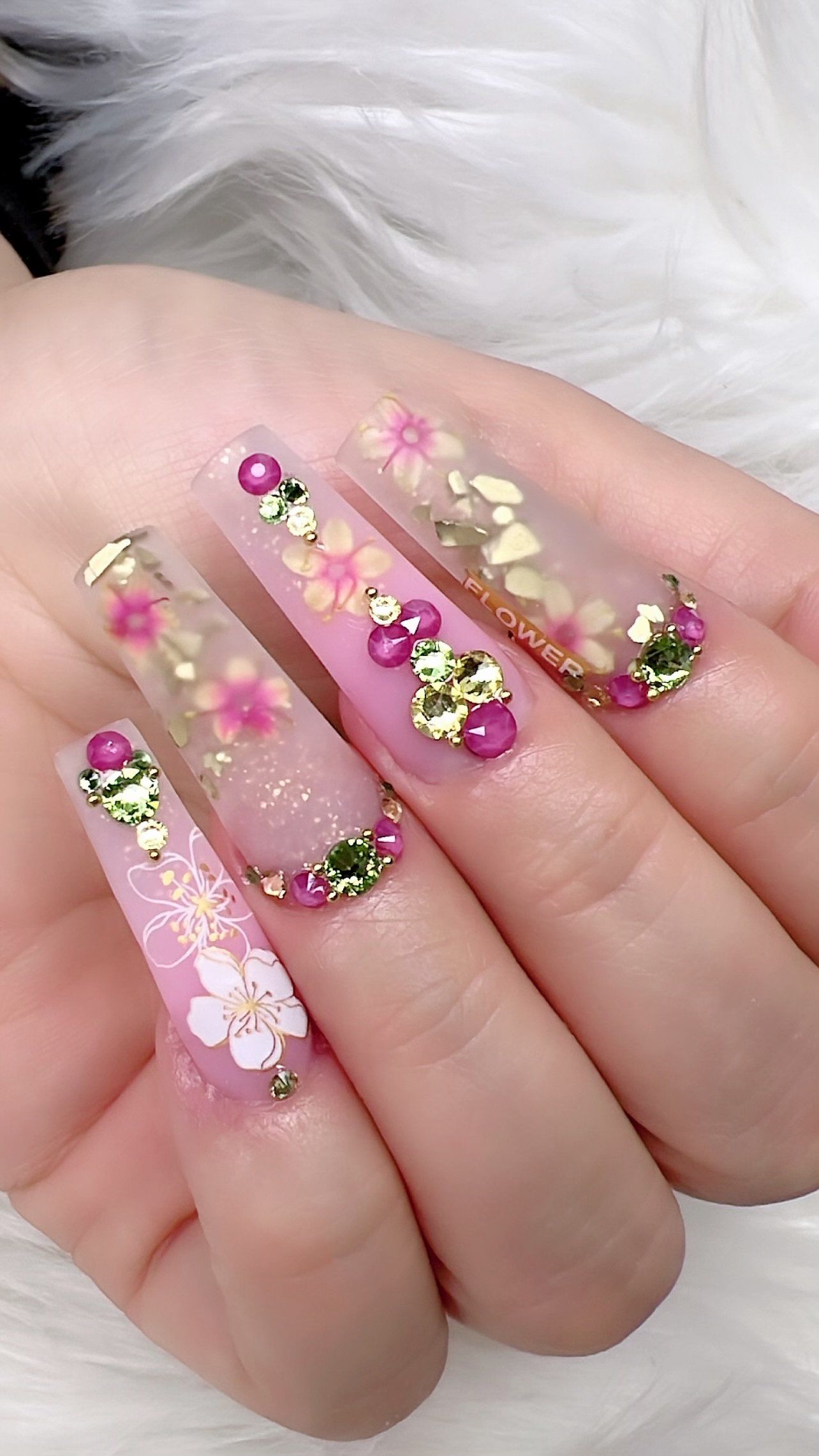 A close up of a person 's hand with long nails and flowers on them.