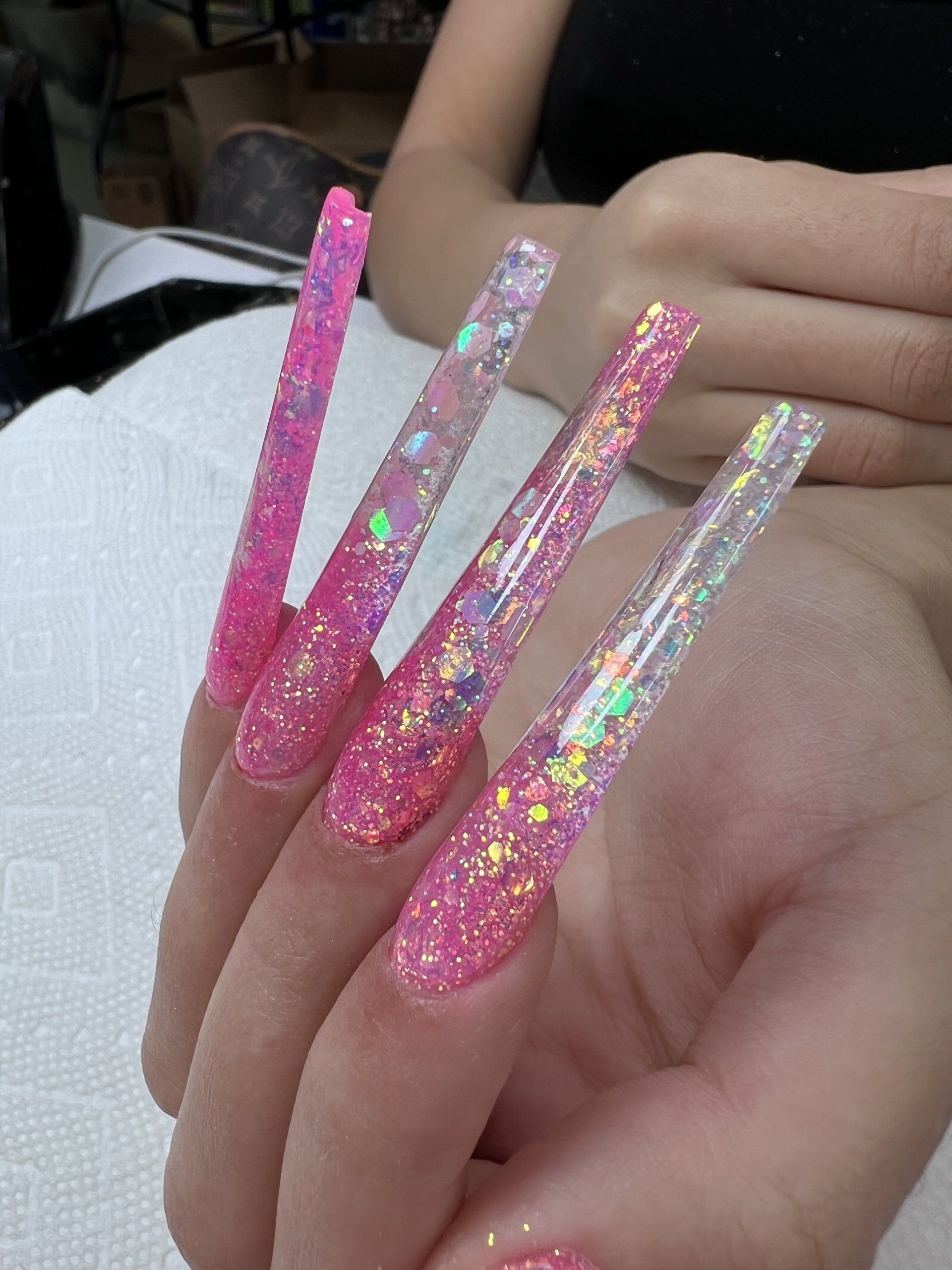 A close up of a person 's hand with long pink nails