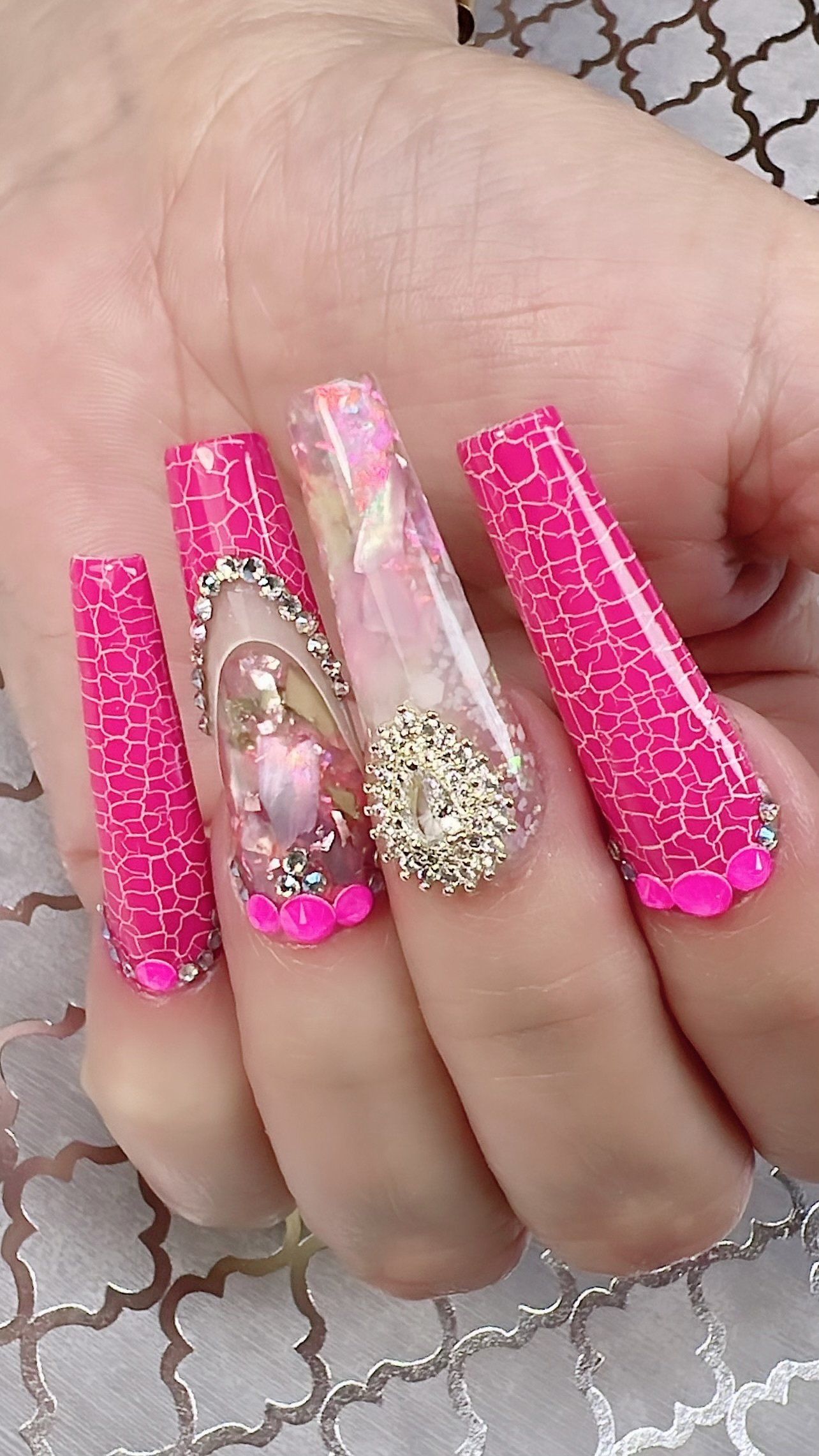 A close up of a person 's hand with long pink nails.