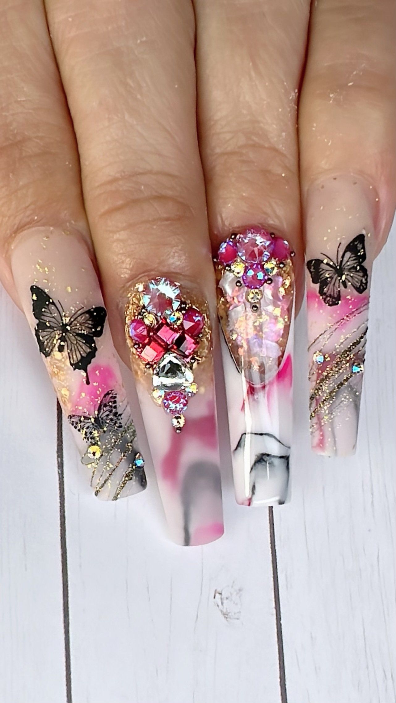 A close up of a person 's nails with butterflies and rhinestones.