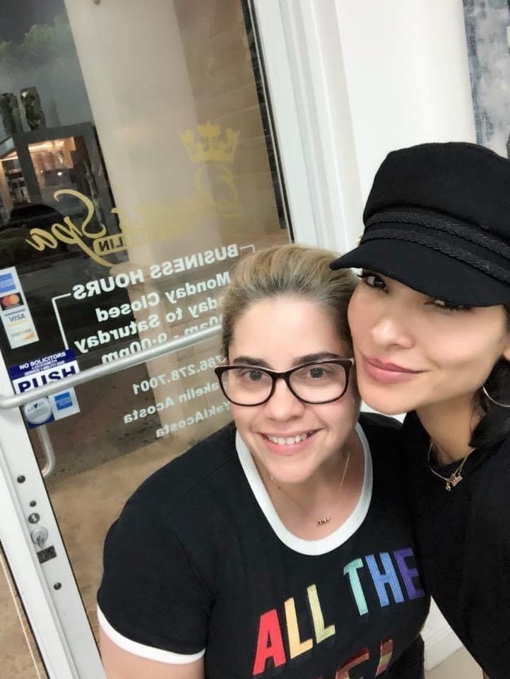 Two women posing for a picture with one wearing a shirt that says all the