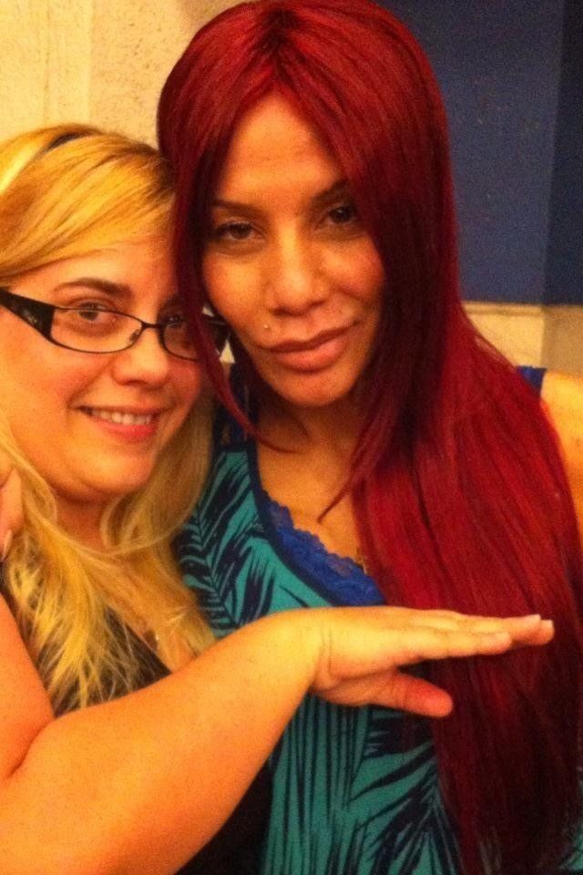 Two women are posing for a picture and one has red hair