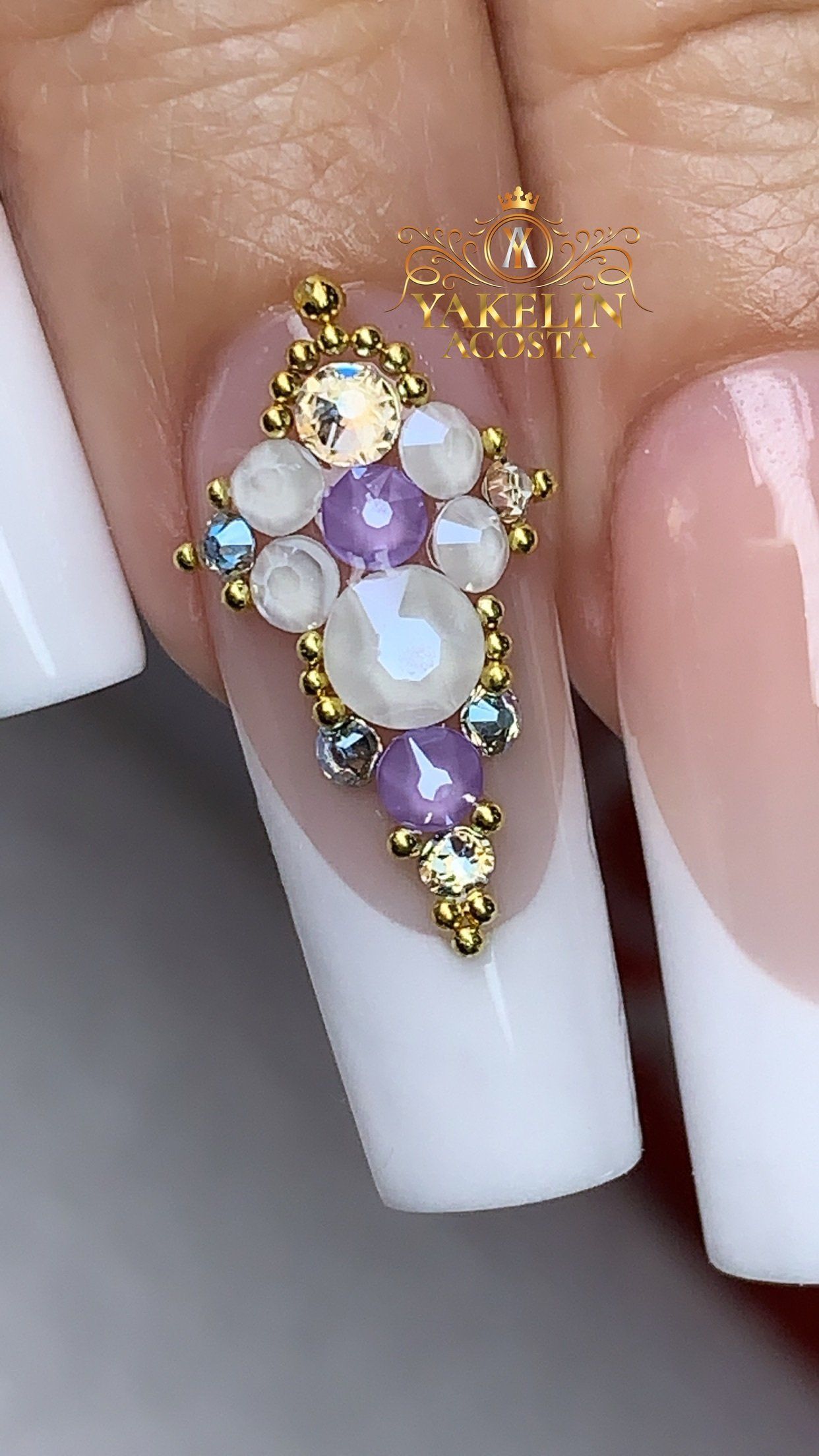 A close up of a woman 's nails with purple and white rhinestones