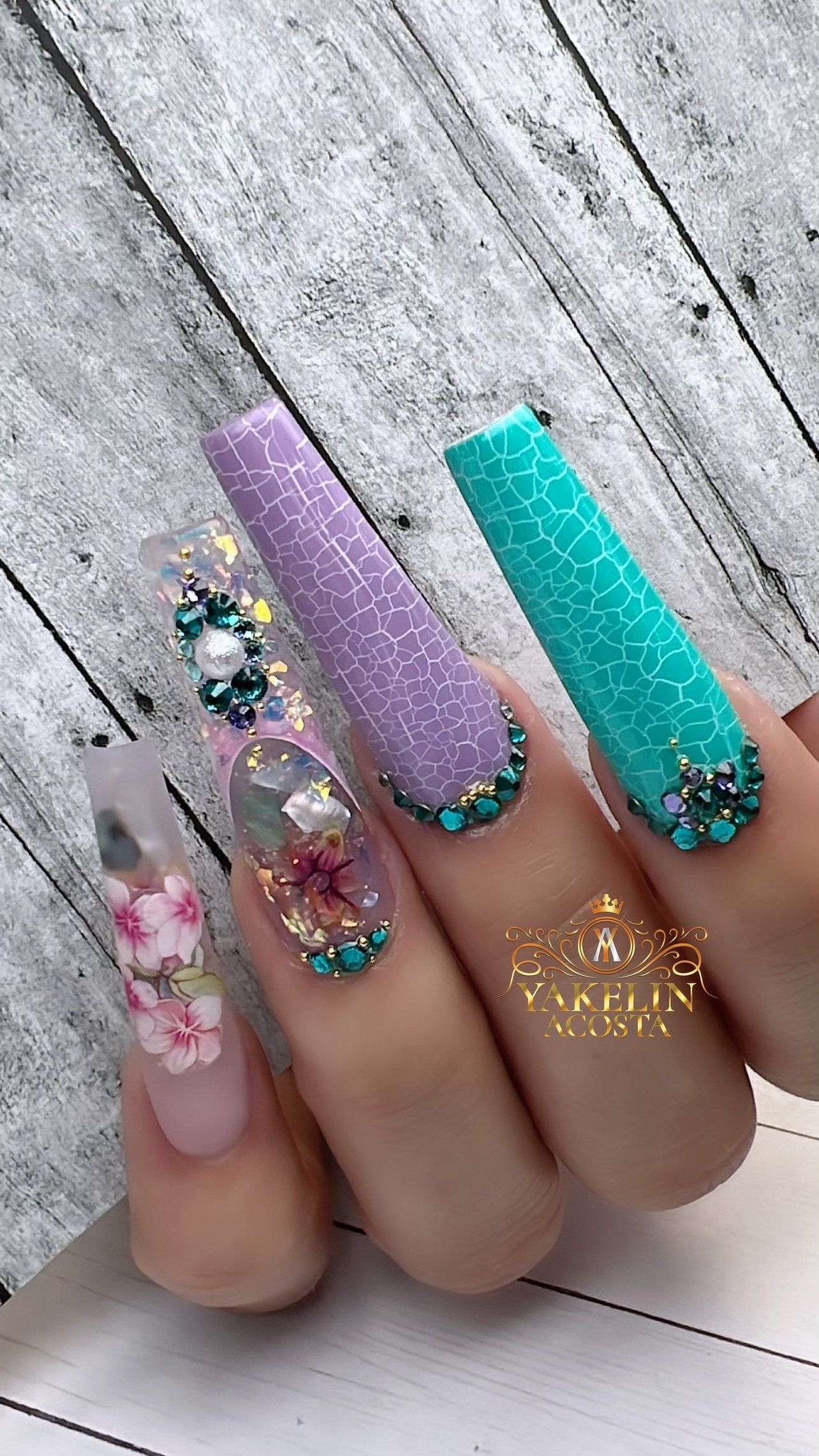 A close up of a person 's nails with flowers and rhinestones.