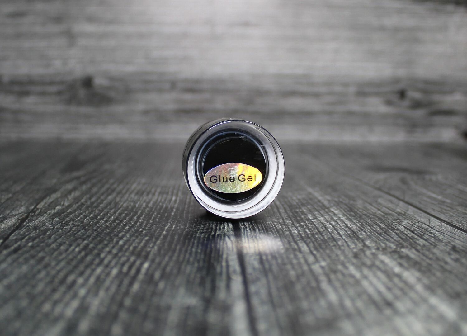 A jar of glue is sitting on a wooden table.