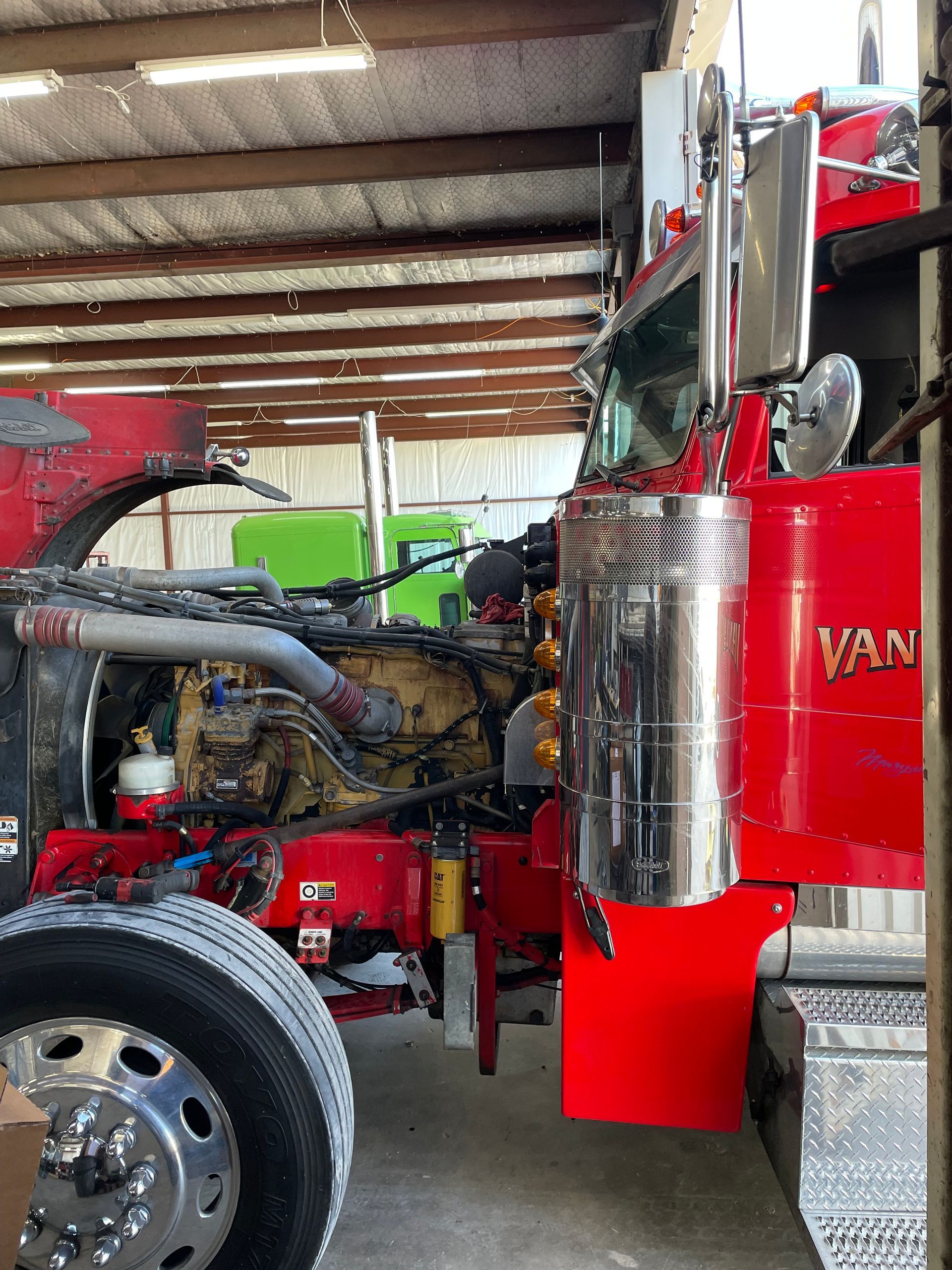 A red semi truck is parked in a garage.