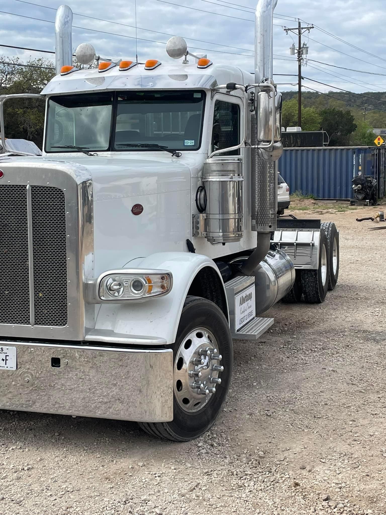 A white semi truck is parked in a gravel lot.