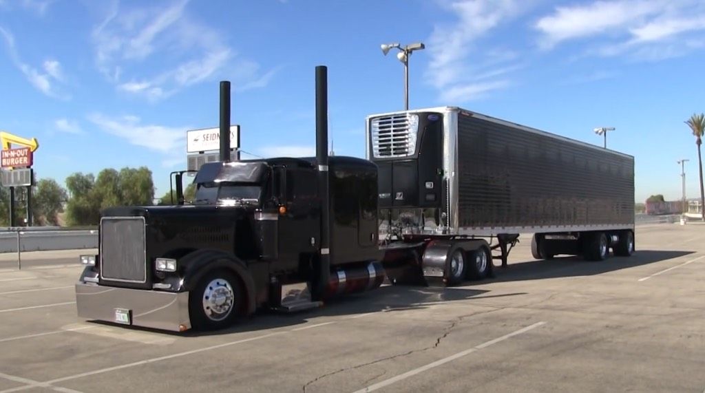 A black semi truck is parked in a parking lot