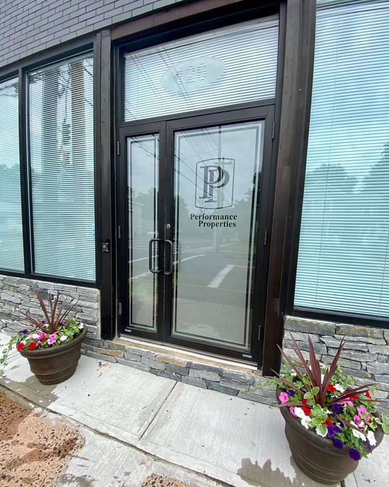 Glass entrance doors to a building with potted flowers on either side