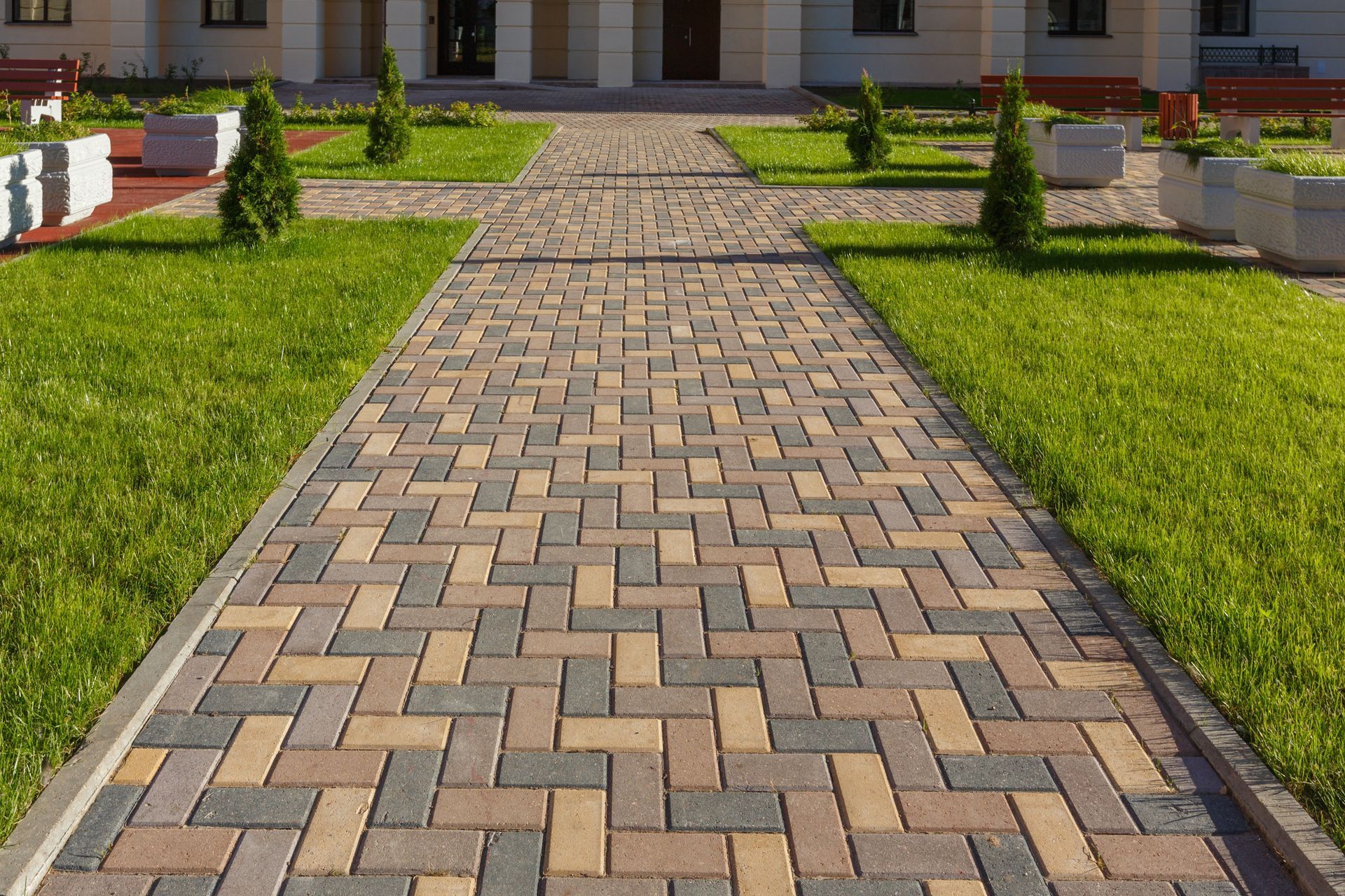 A brick walkway leading to a house in a park.
