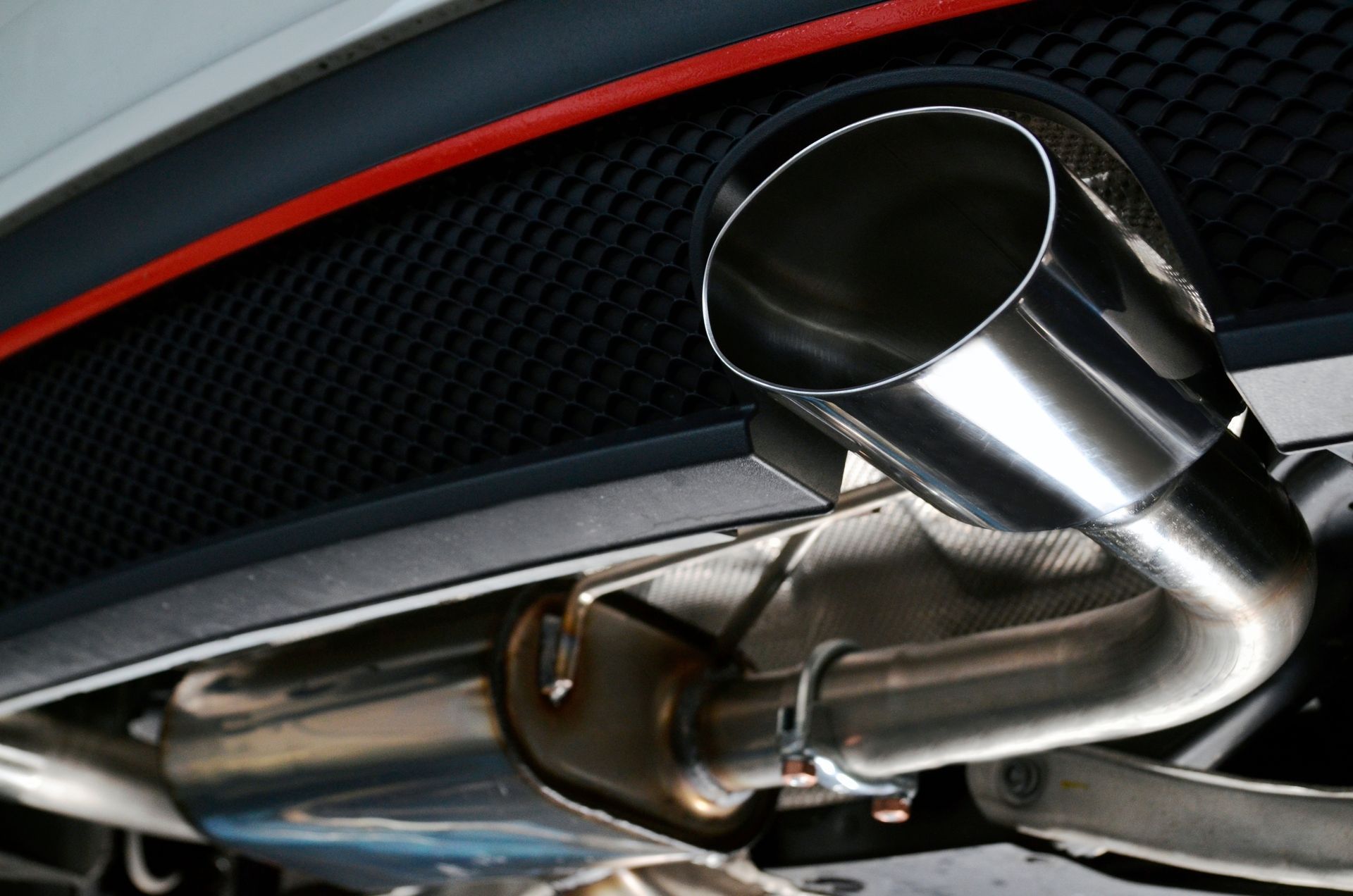 A close up of a stainless steel exhaust pipe on the back of a car.