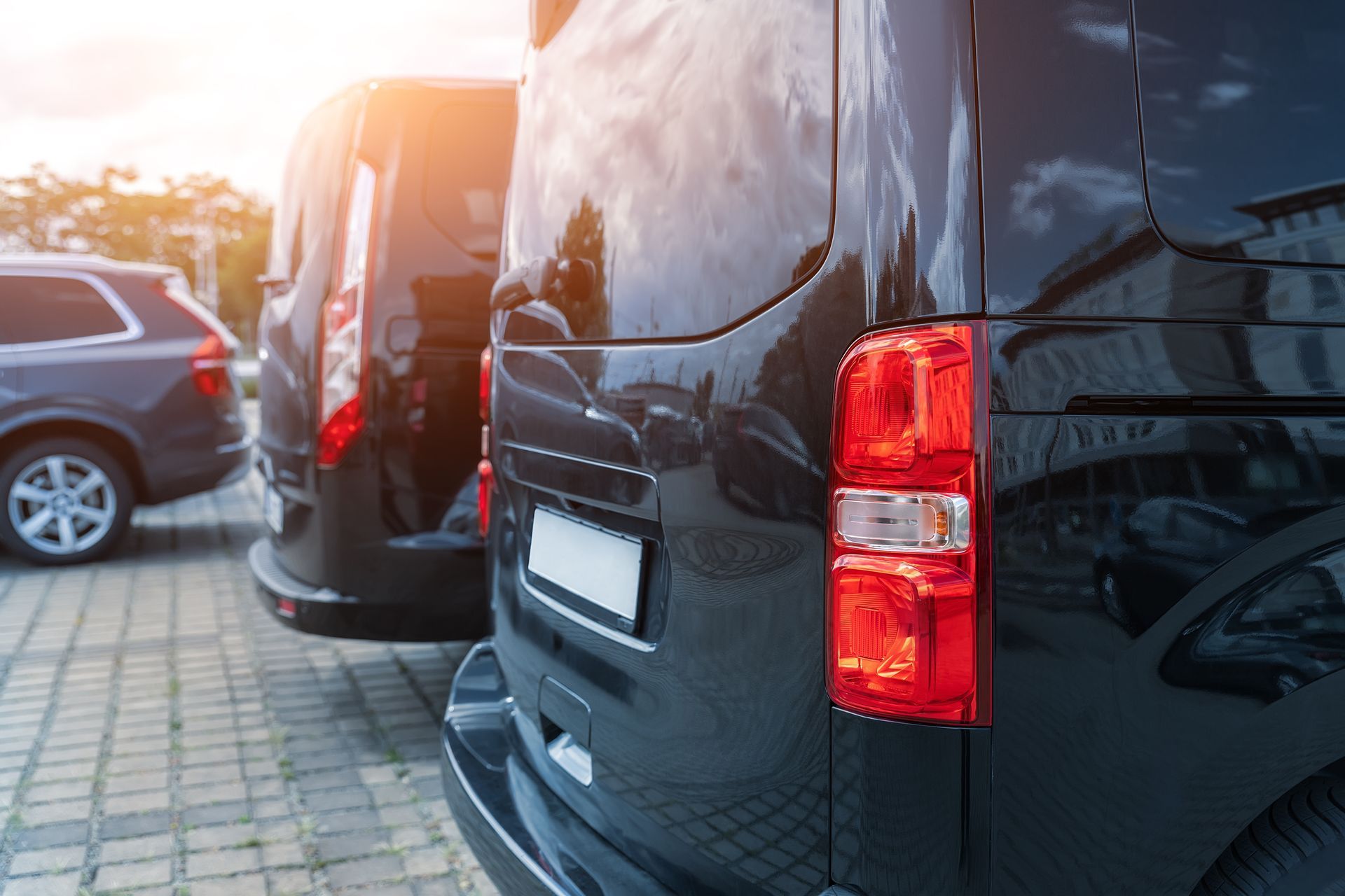 A row of black vans parked next to each other in a parking lot.