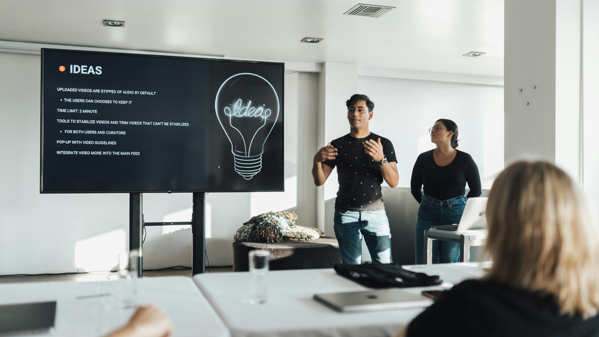 A presenter stands before a screen titled 
