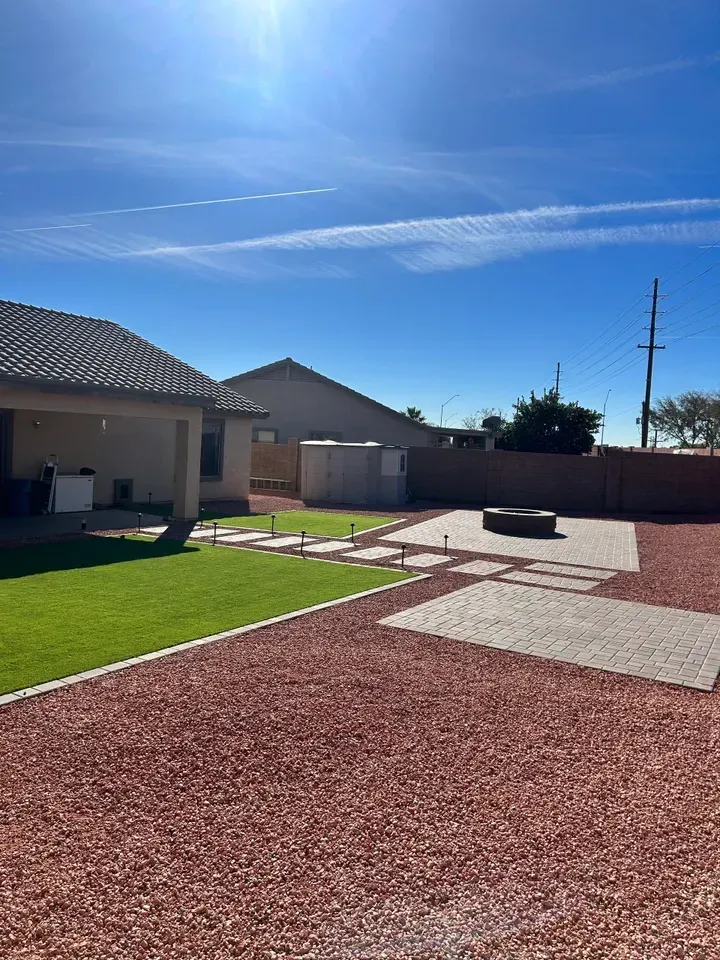 There is a house in the background and a lot of gravel in the foreground.