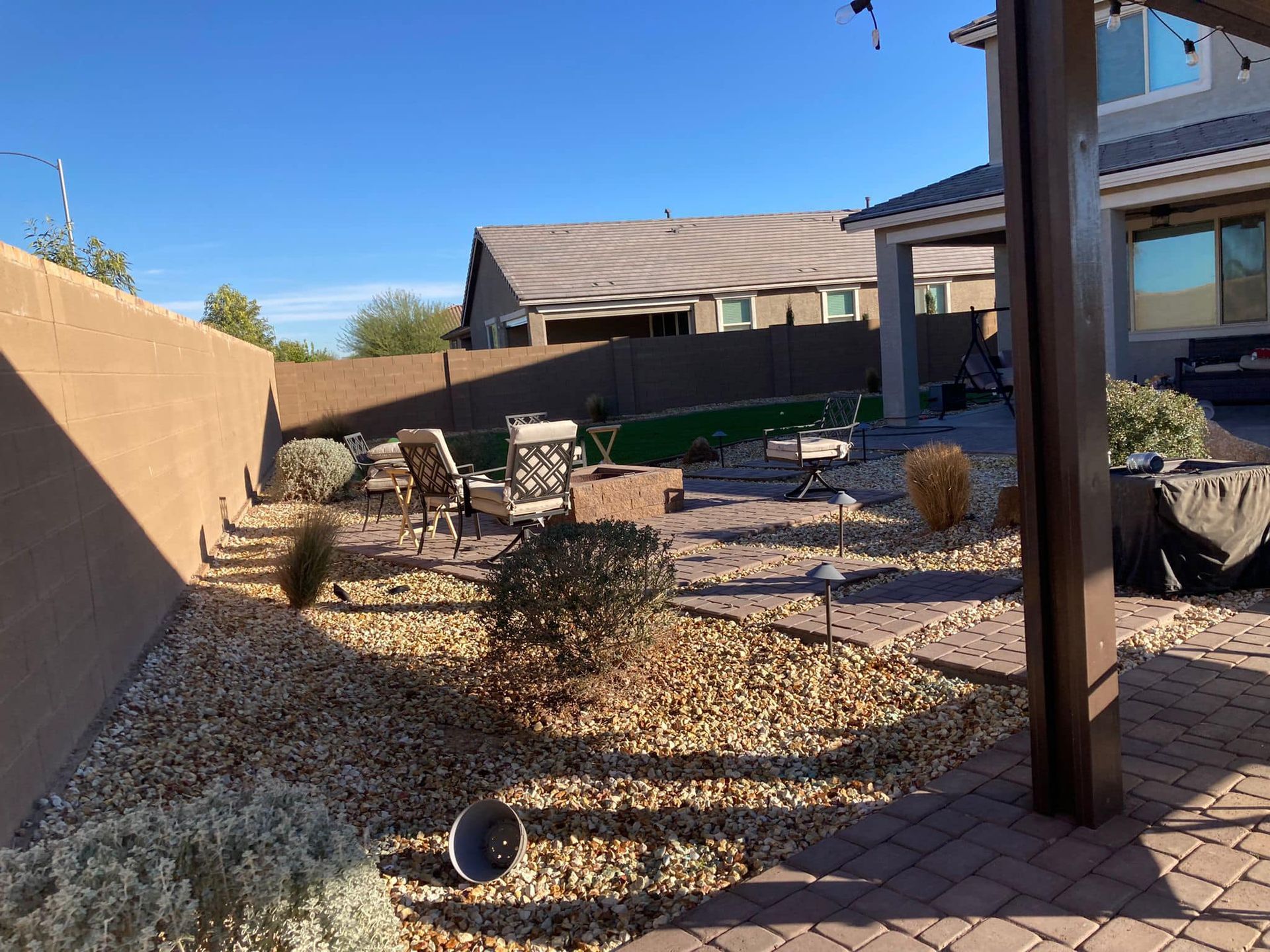 The backyard of a house with a patio area and a fence.