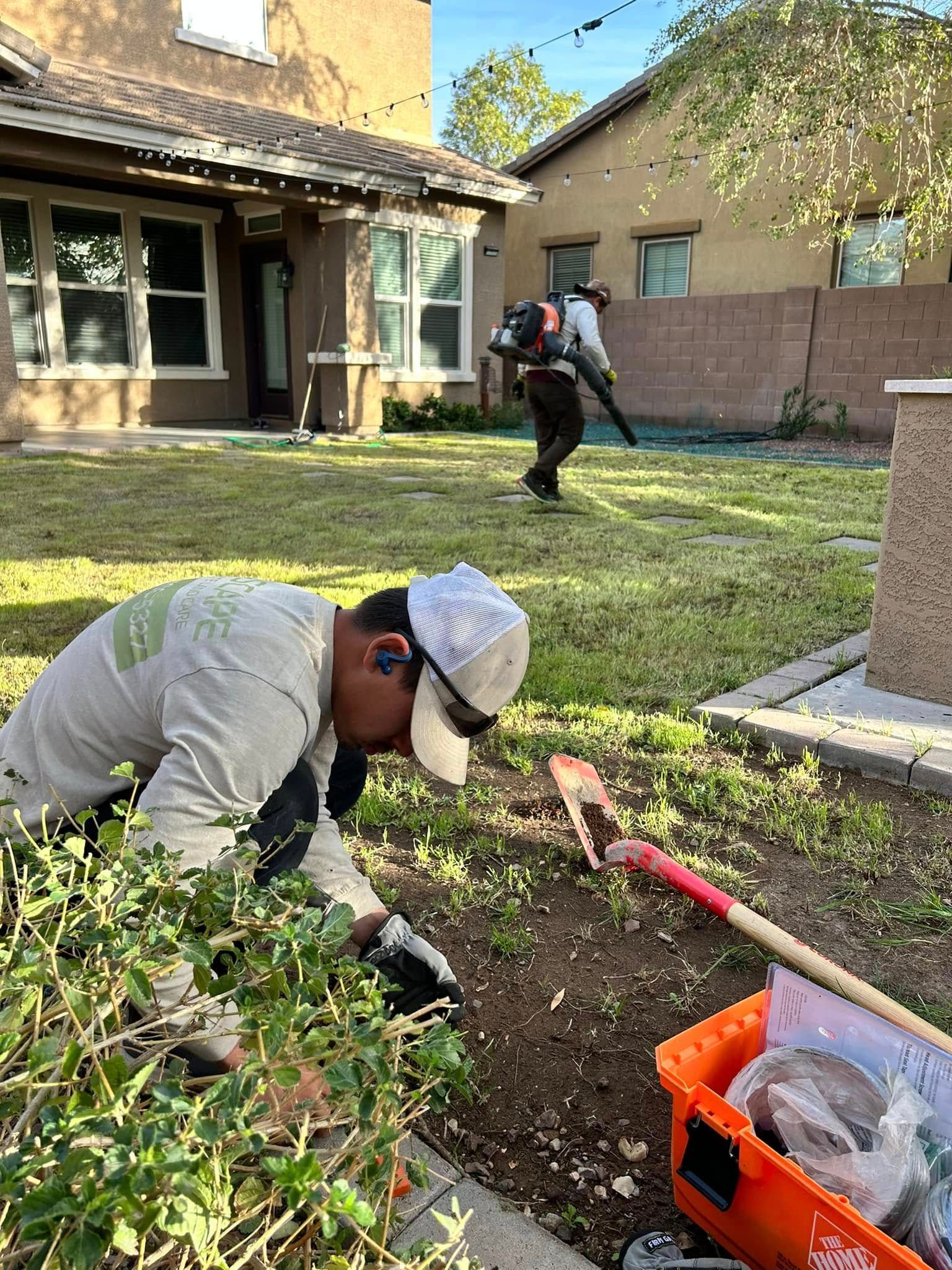 A man is kneeling down in the dirt in front of a house.