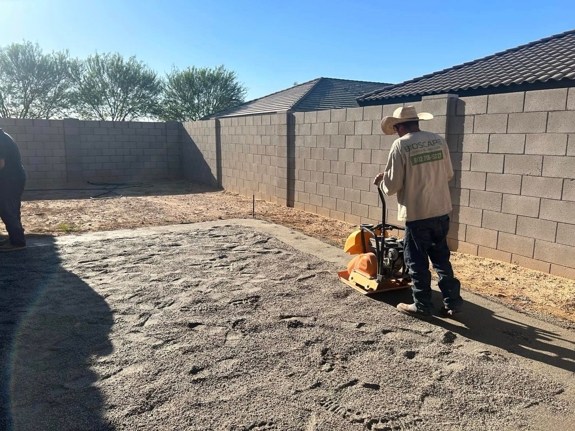 A man in a cowboy hat is using a machine to level the ground