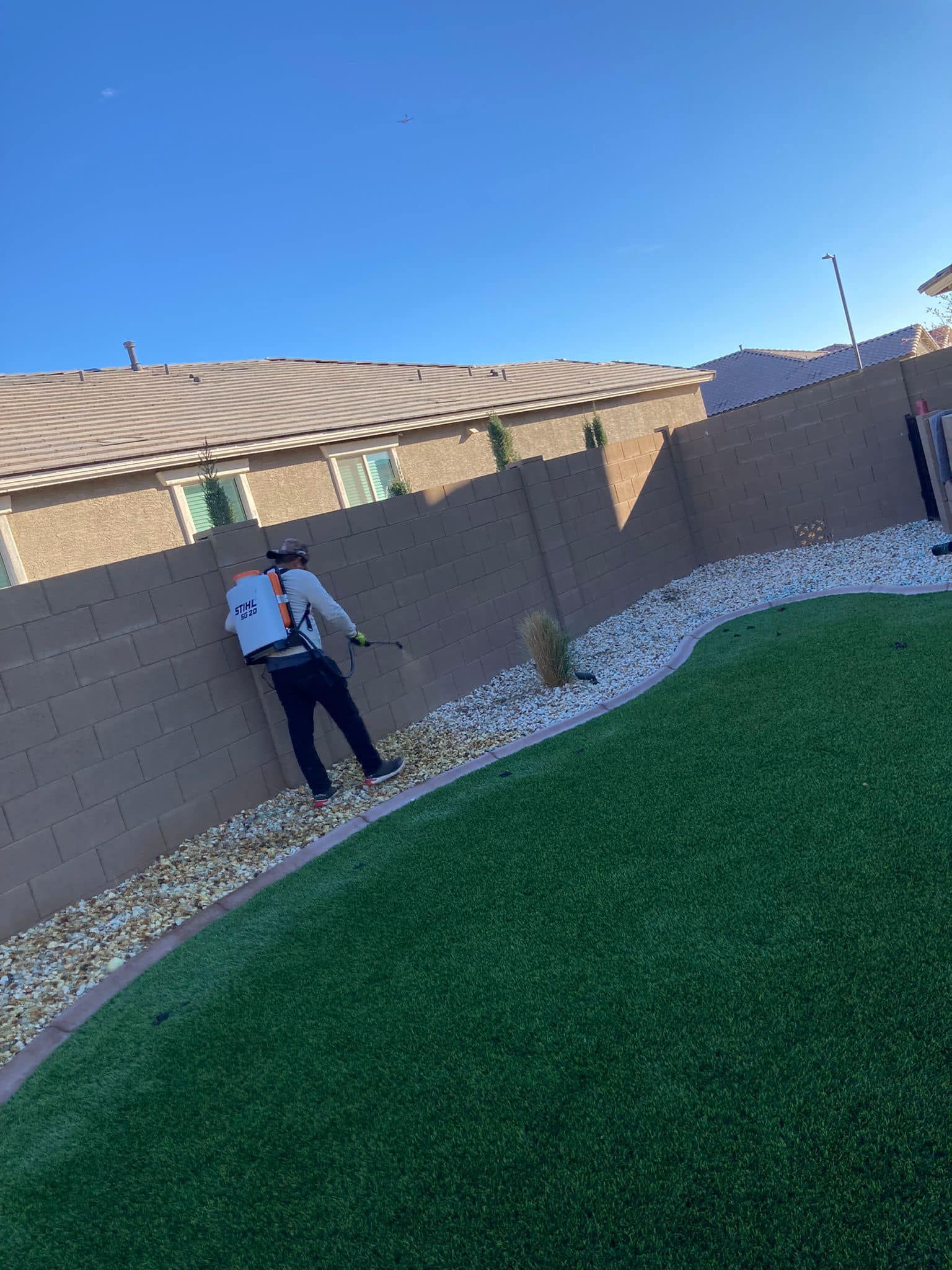 A man is cutting grass in a backyard with a lawn mower.